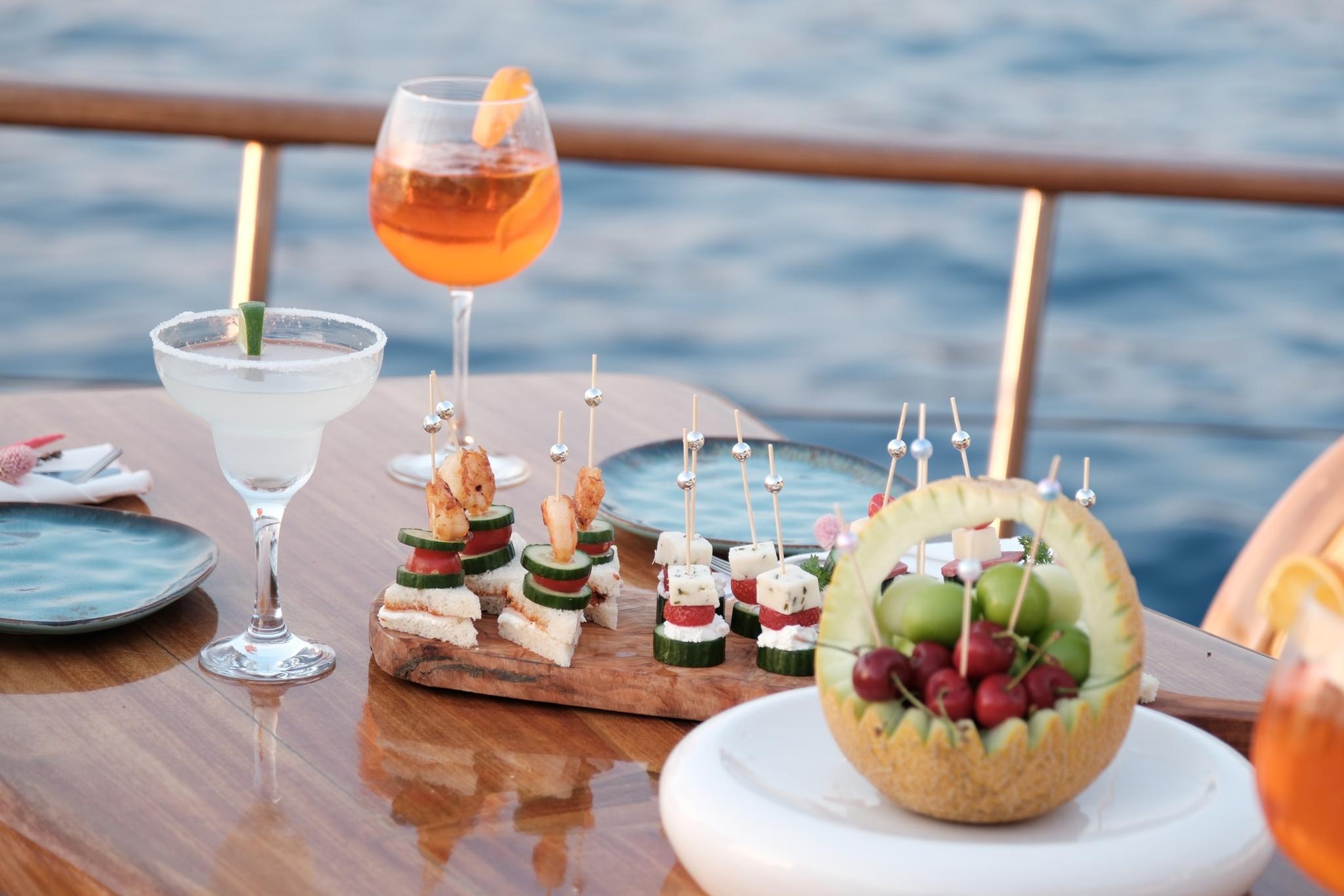 cocktails and gourmet appetizers with canapes served on yacht deck dining table