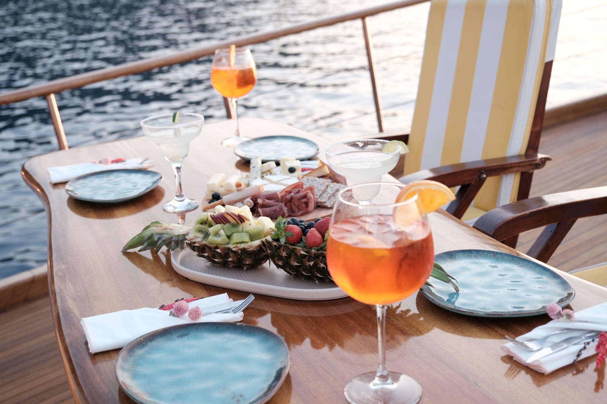 yacht deck dining table with orange cocktails and fruit appetizer platter overlooking water