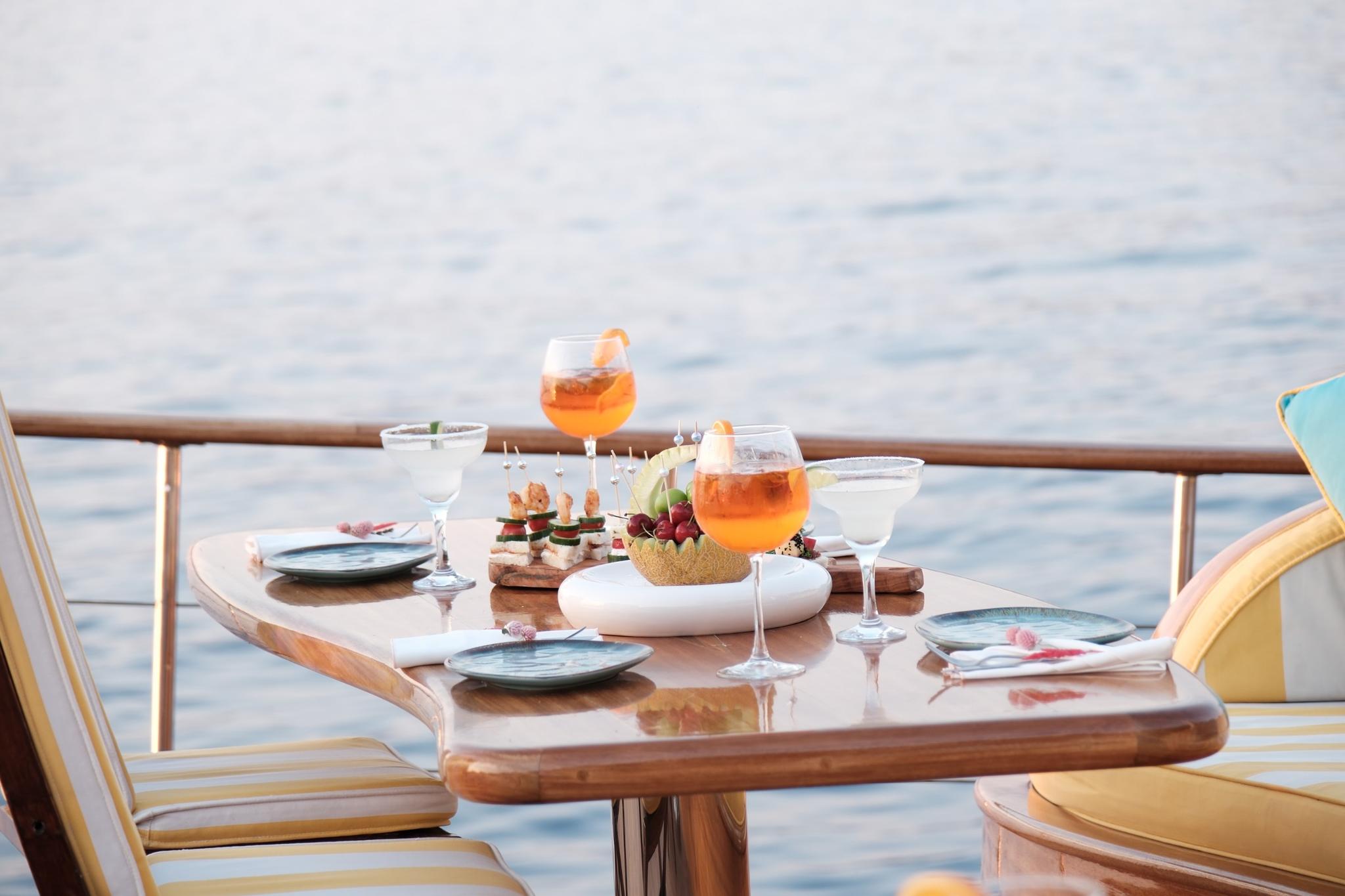 yacht dining table with orange cocktails, appetizer platters and table setting overlooking ocean