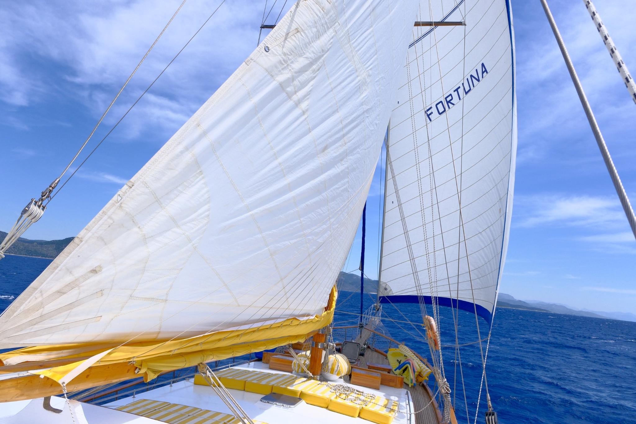 Sailing yacht Fortuna with white sails unfurled cruising blue Mediterranean waters