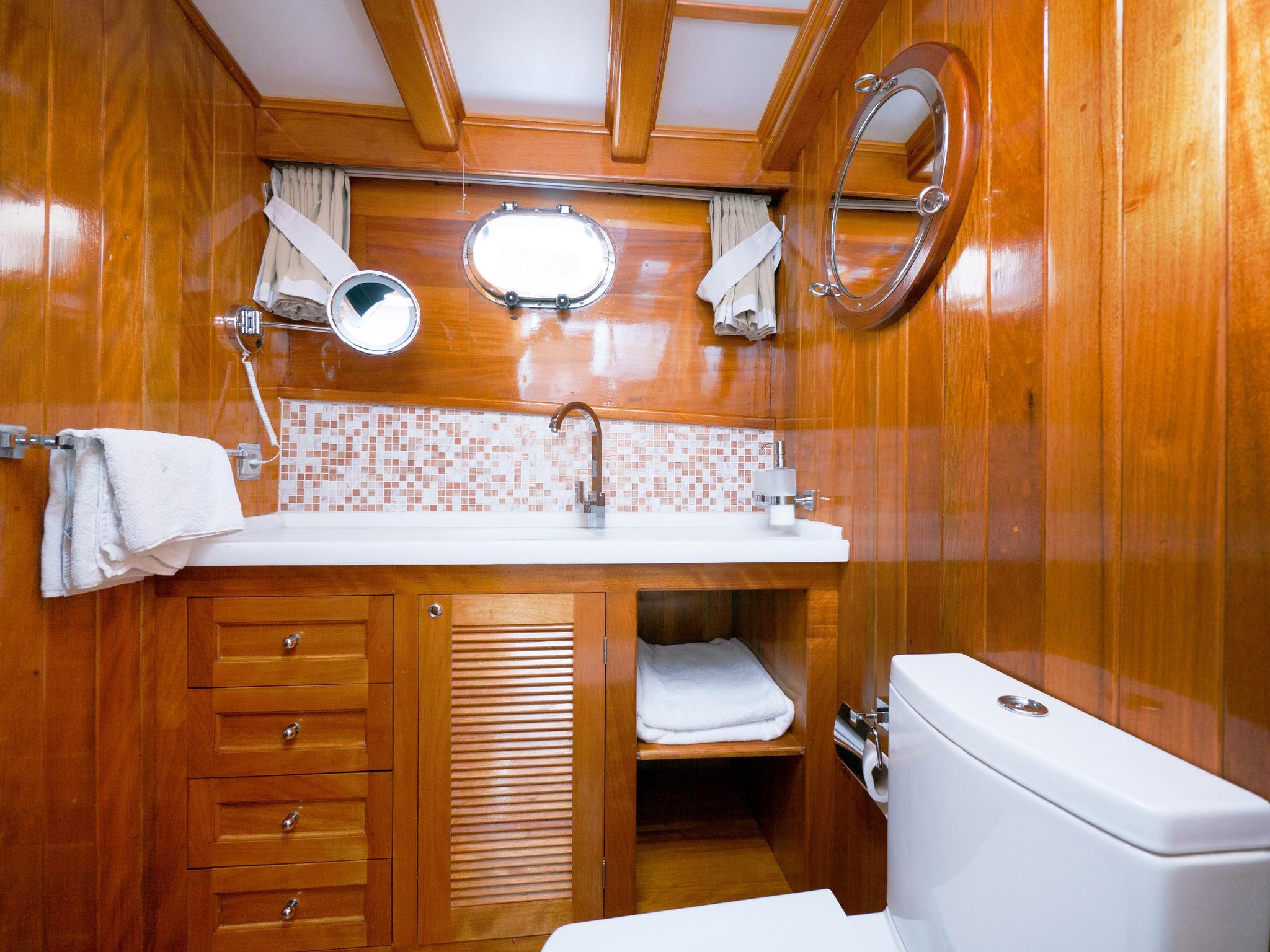 yacht bathroom featuring white vanity sink with mosaic tile backsplash and toilet