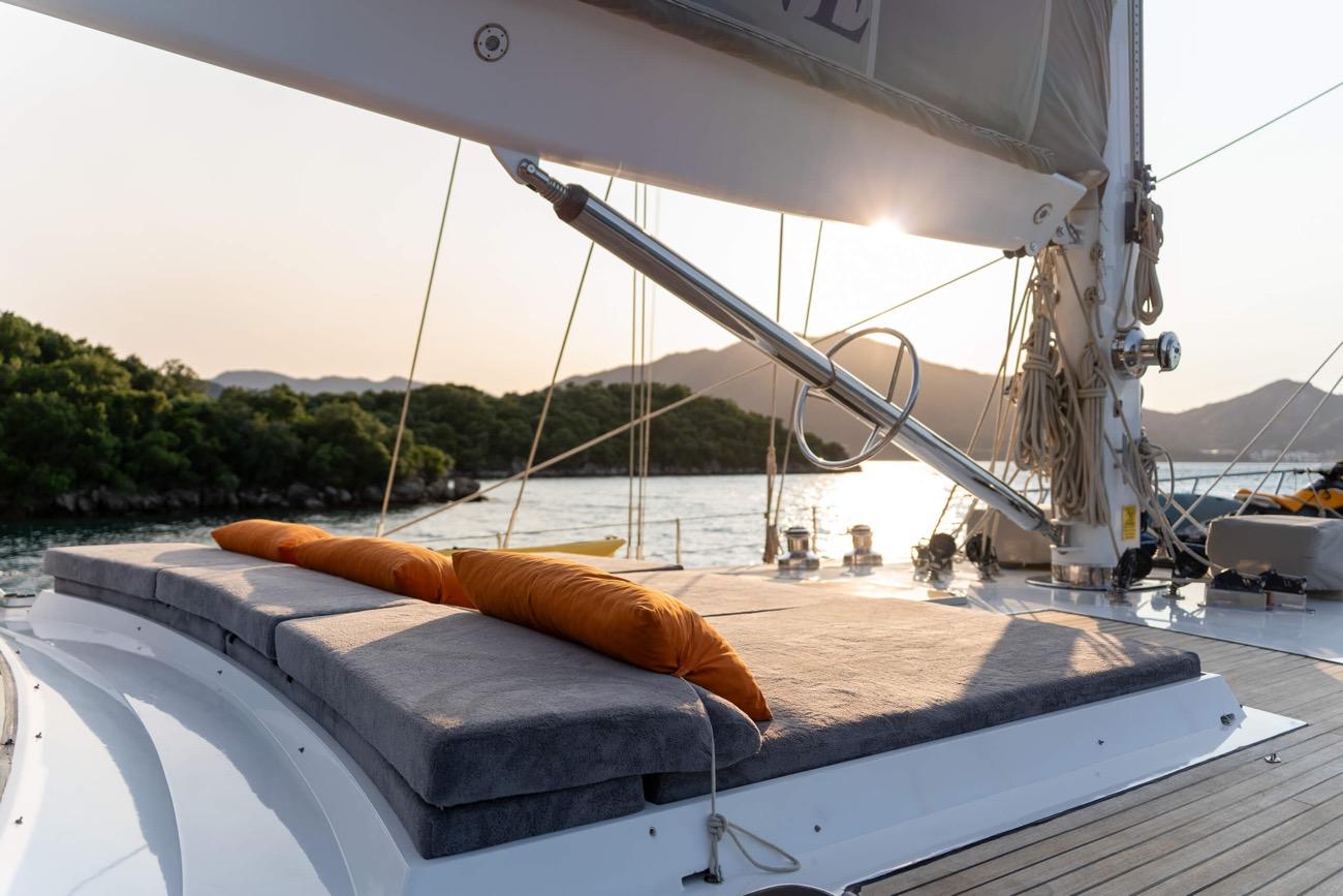 bow sun deck with grey cushioned seating and orange bolster pillow at sunset