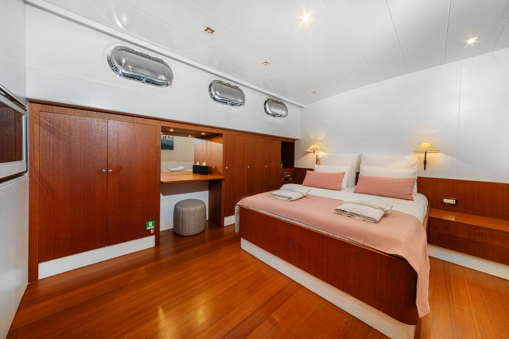 yacht guest cabin interior with double bed, built-in wardrobes, and vanity desk area