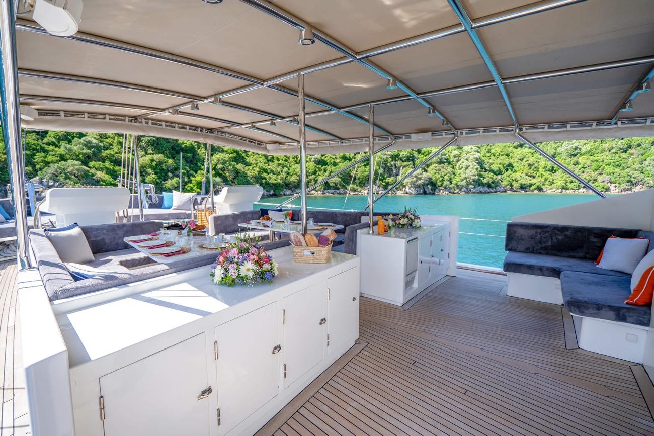 yacht aft deck with dining table, built-in seating, white cabinetry and teak decking