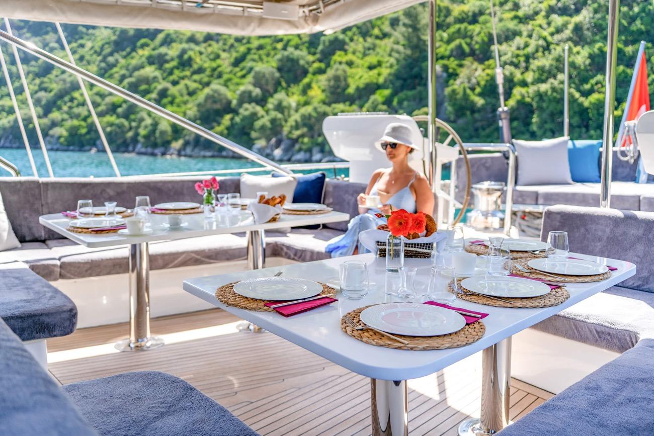 yacht aft deck dining area with set tables, wicker placemats, and guest enjoying meal