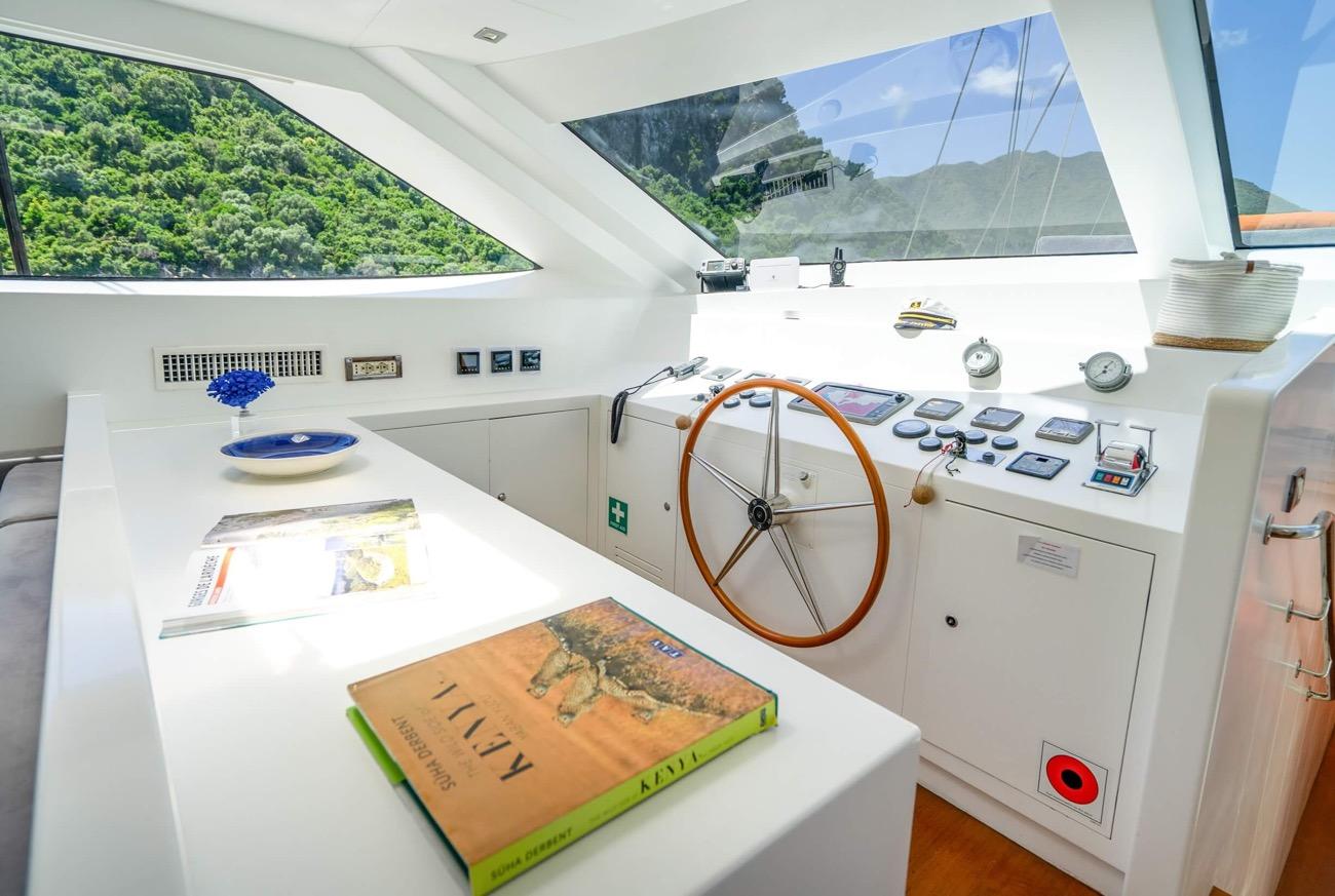 yacht wheelhouse interior with wooden steering wheel, navigation instruments, and panoramic windows