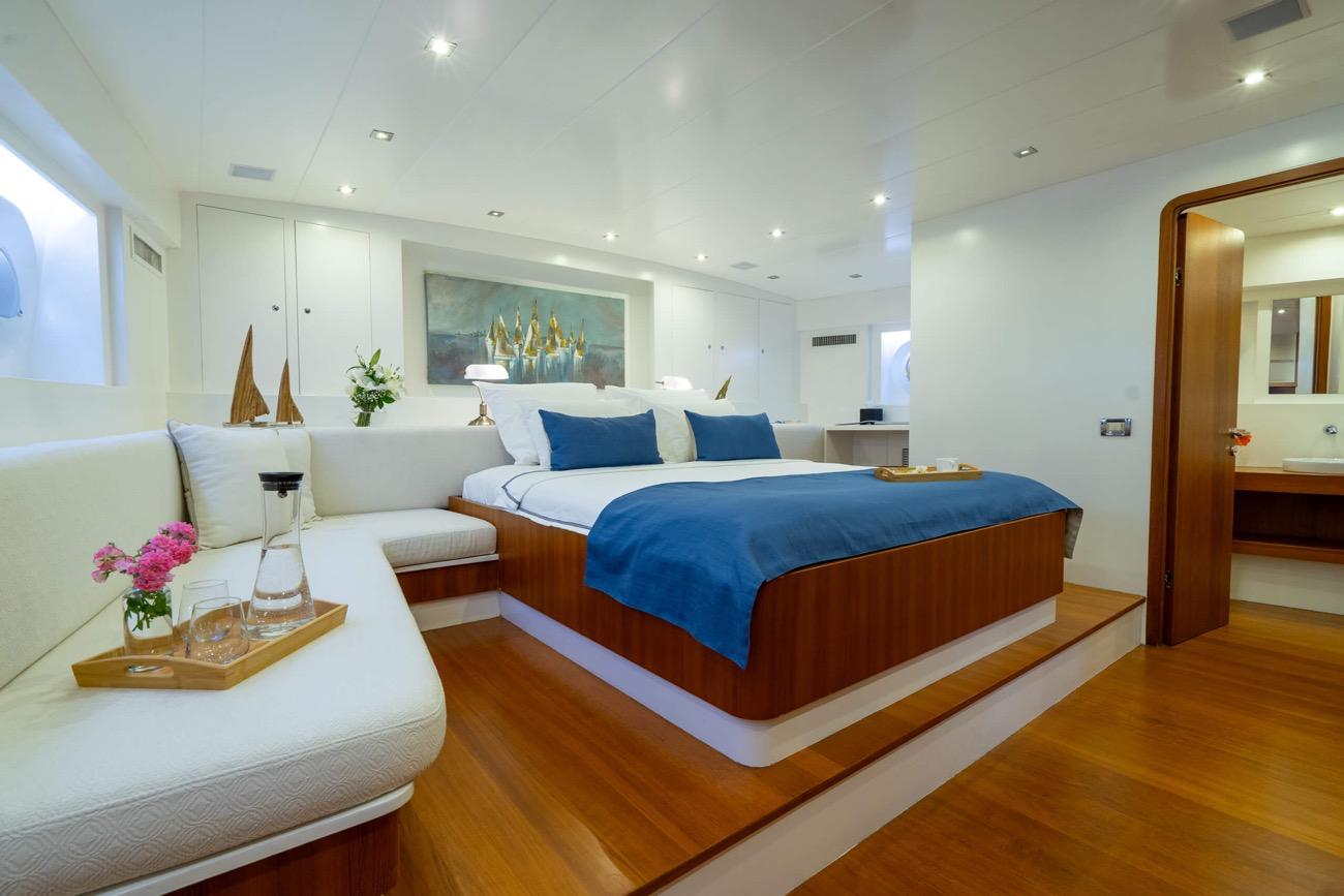 luxury yacht master cabin featuring king bed with blue bedding, white seating area, and en-suite entrance