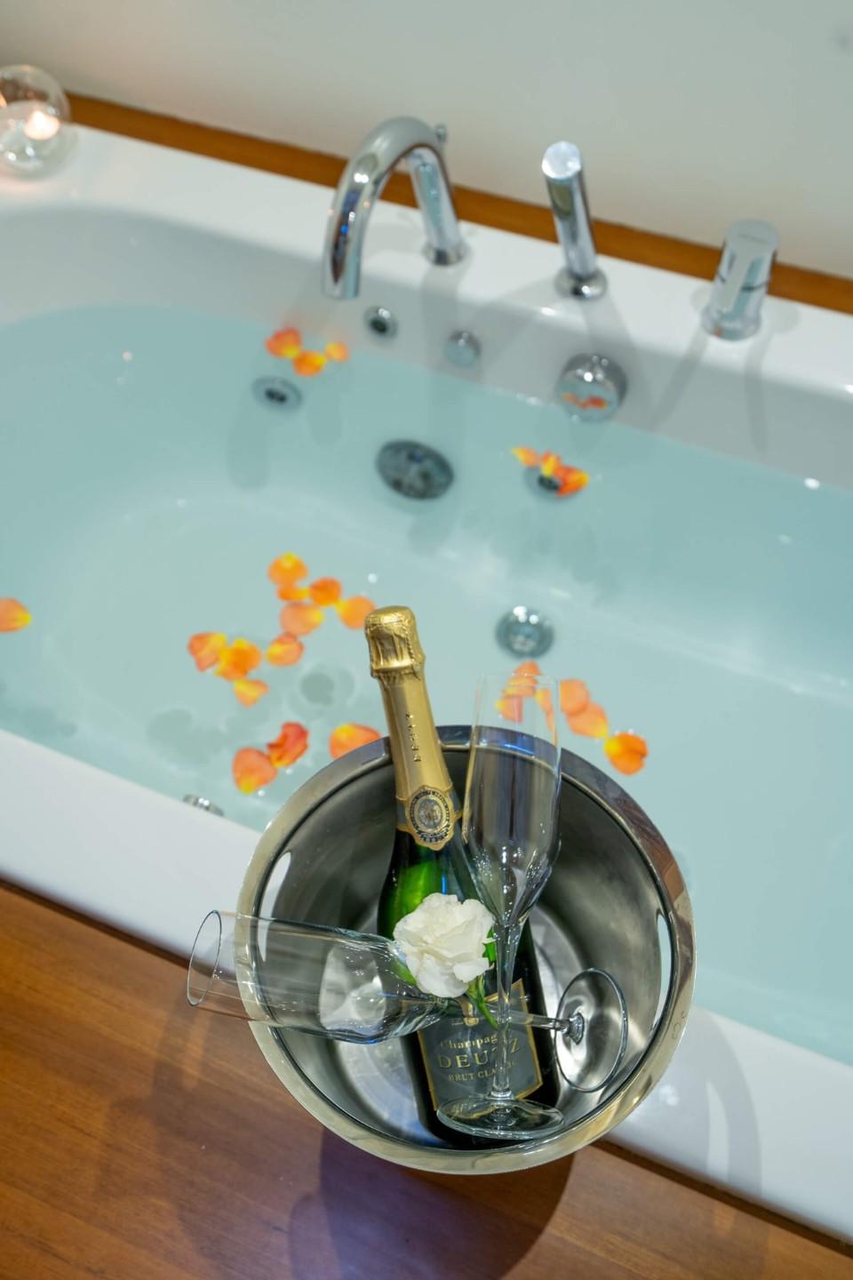 luxury yacht jacuzzi filled with water, orange rose petals, champagne bucket with bottle and glasses