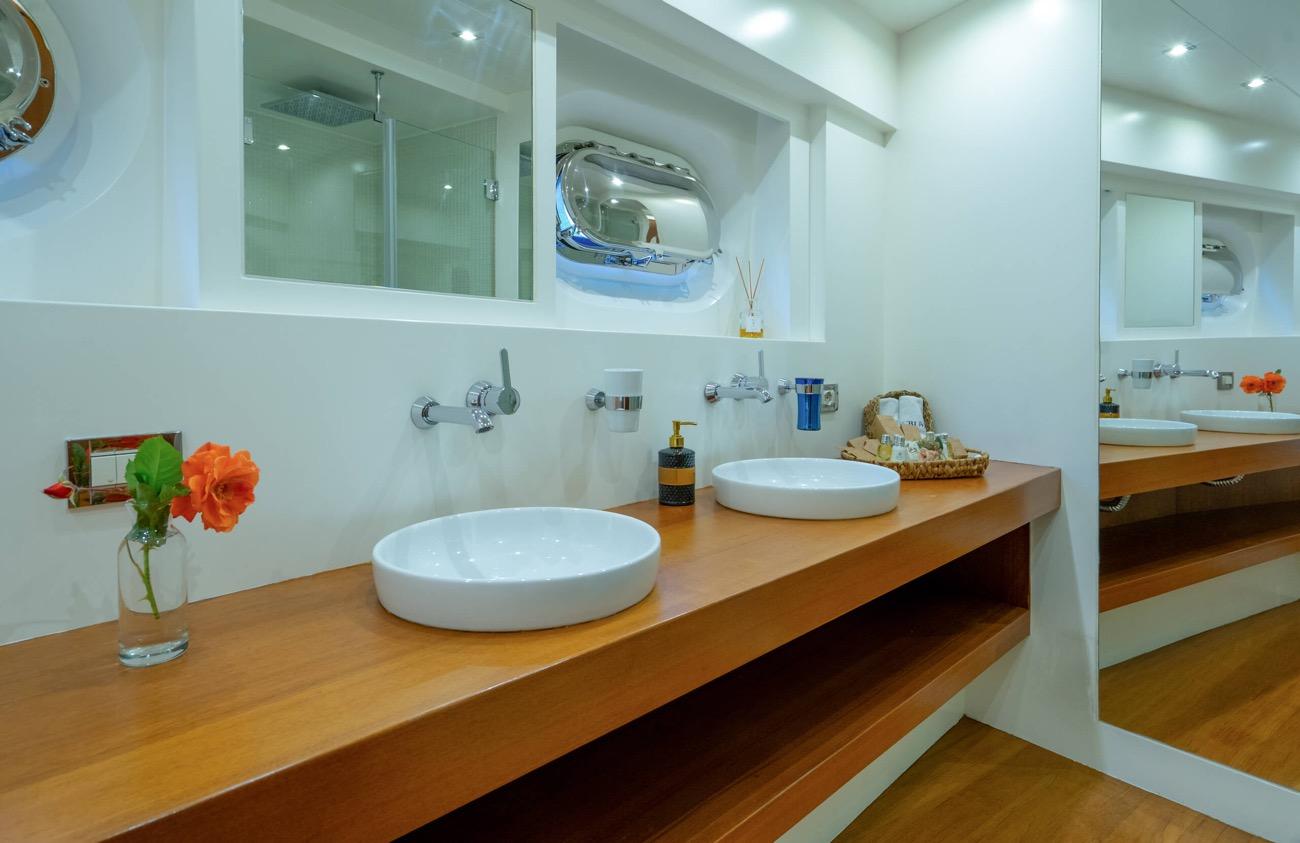 yacht bathroom featuring twin white vessel sinks on wooden vanity with wall-mounted mirrors