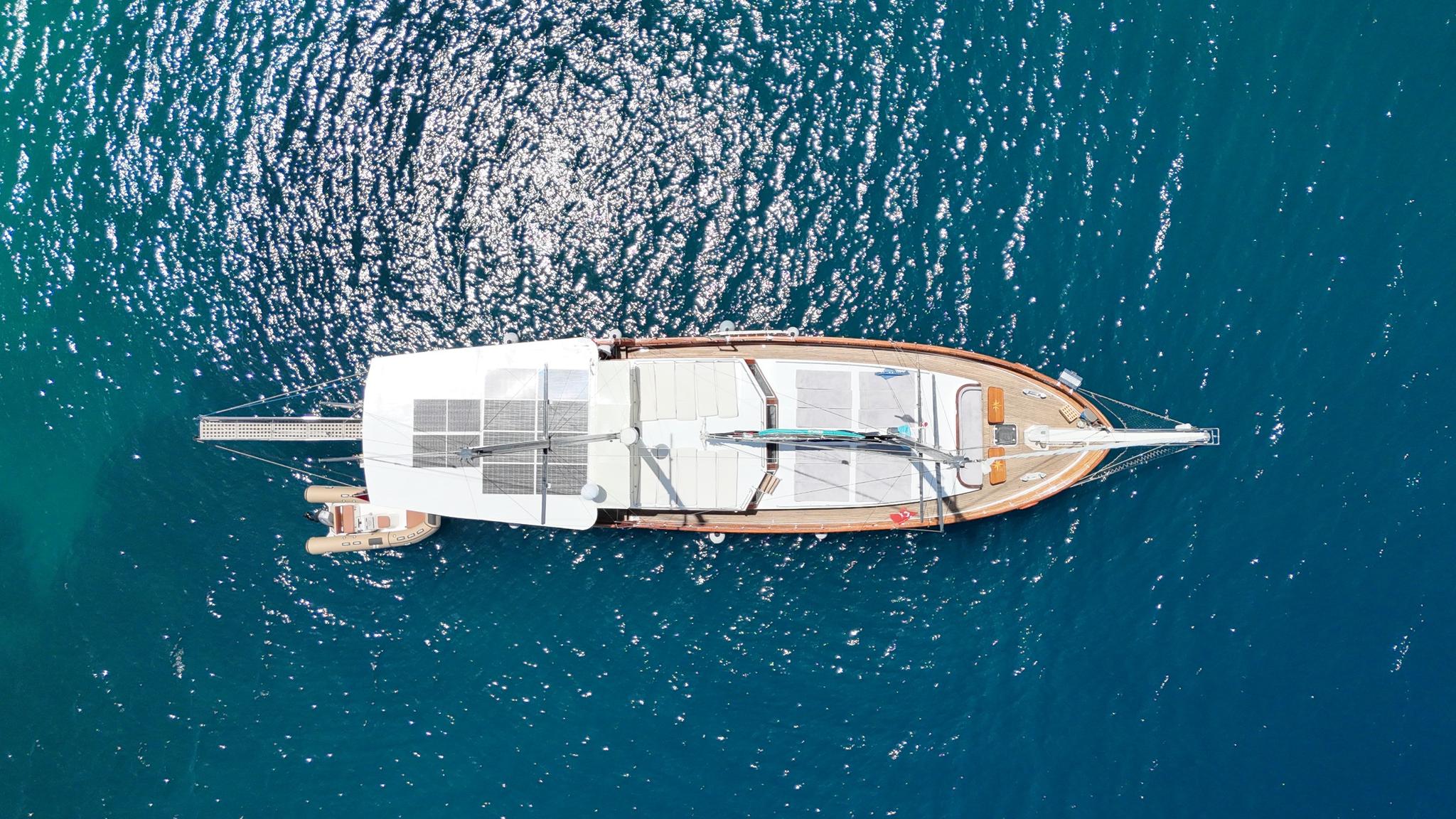 aerial view of white luxury yacht with teak decking anchored in crystal clear turquoise waters