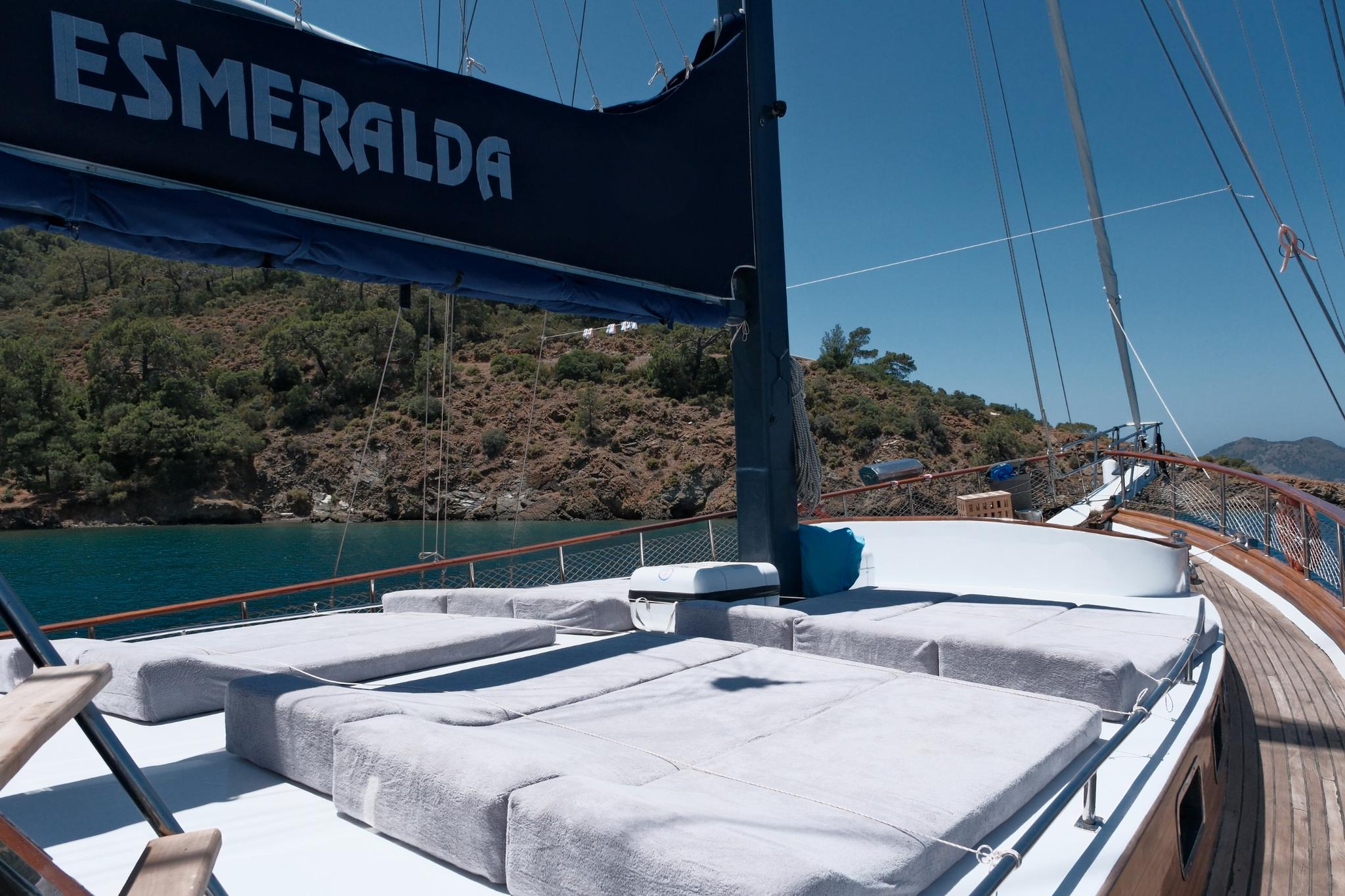 gulet Esmeralda forward deck lounge with white cushioned seating and blue sail