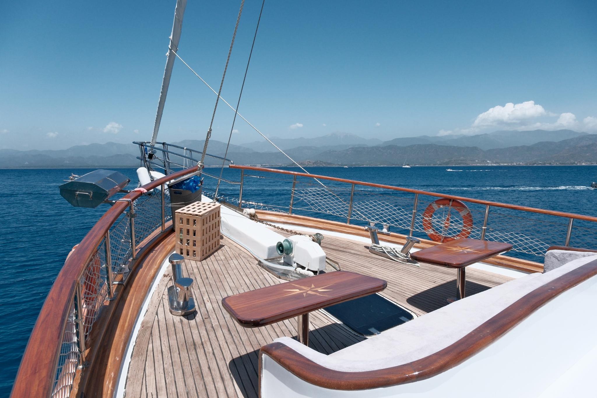 gulet forward deck with teak planking, sailing mast, rigging and wooden dining table