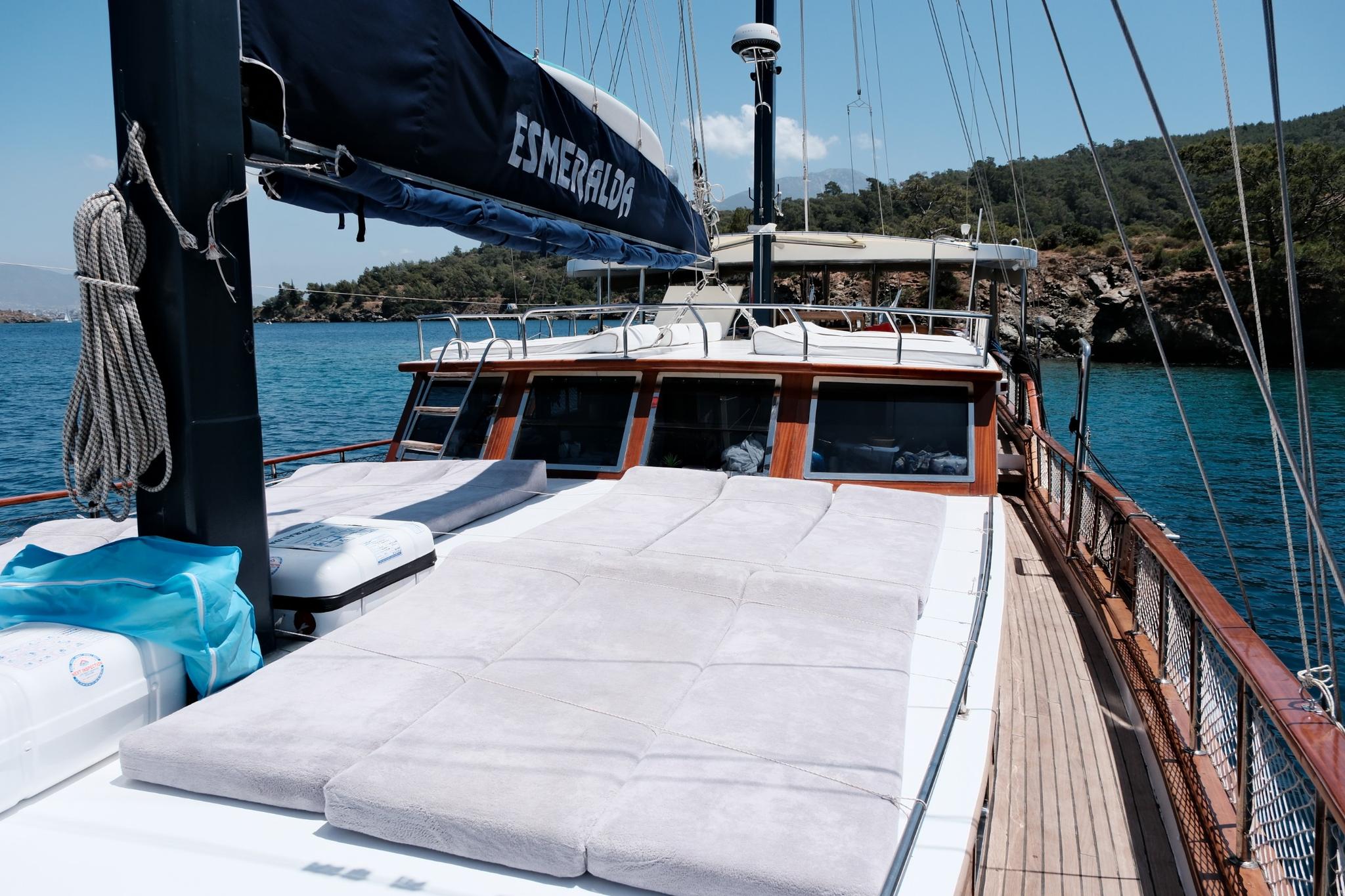 gulet bow deck with white sun loungers and cushions overlooking turquoise waters