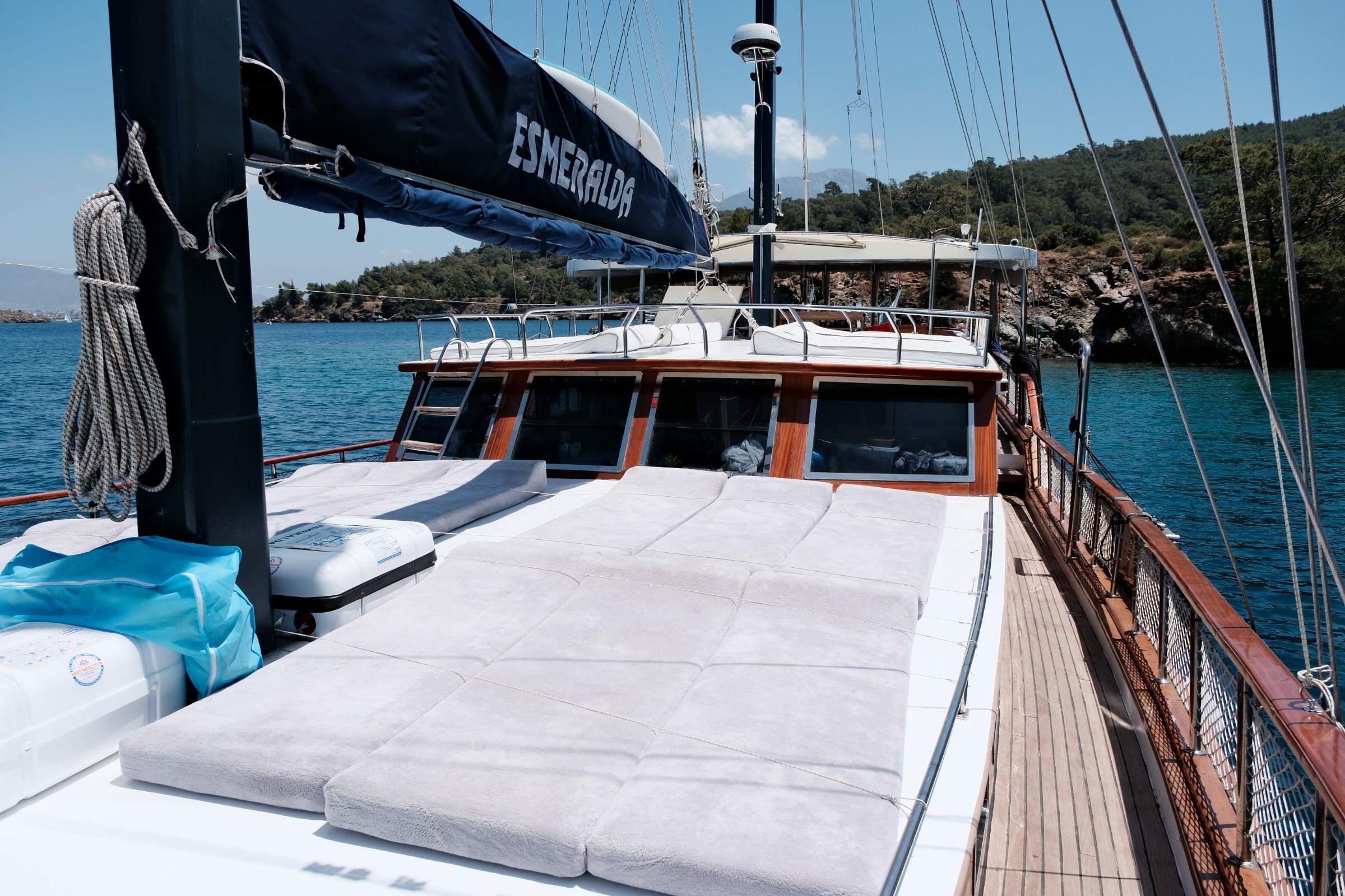 gulet bow deck with white sun loungers and cushions overlooking turquoise waters