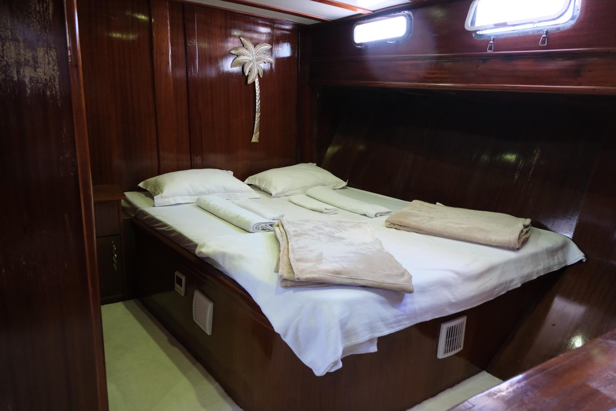 yacht guest cabin interior with double bed white linens mahogany wood paneling