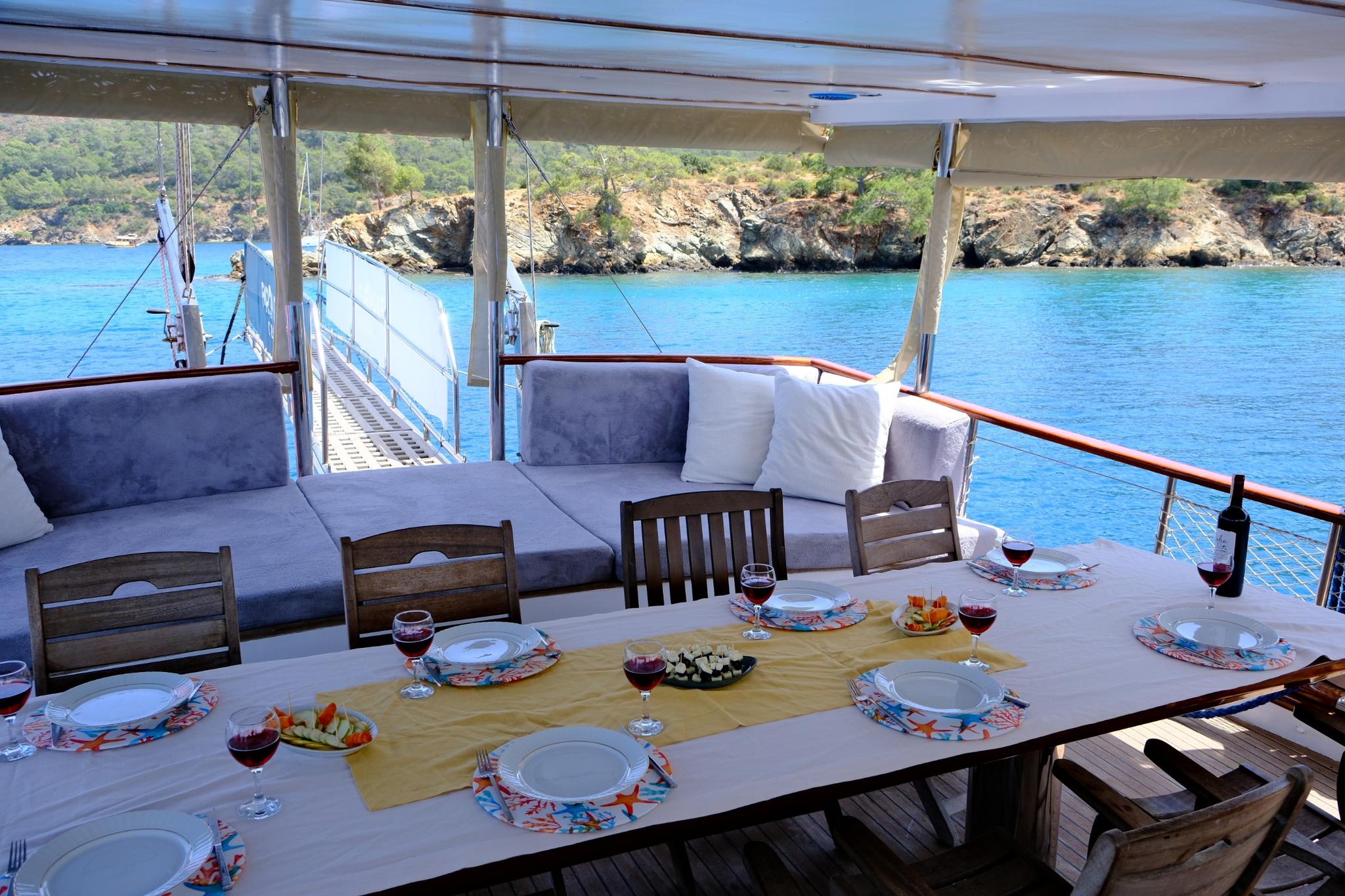 Yacht aft deck dining area with formal table setting featuring plates wine glasses and appetizers