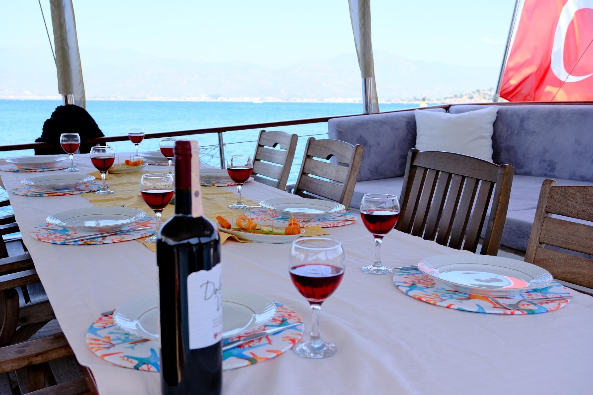yacht dining table set with wine glasses, colorful placemats, and red wine service