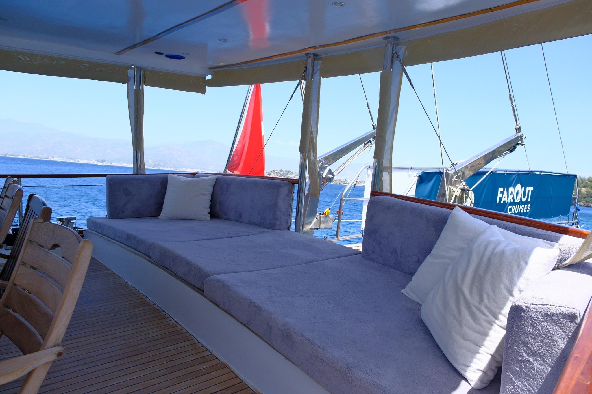 Gulet aft deck lounge area with blue cushioned seating under white canopy