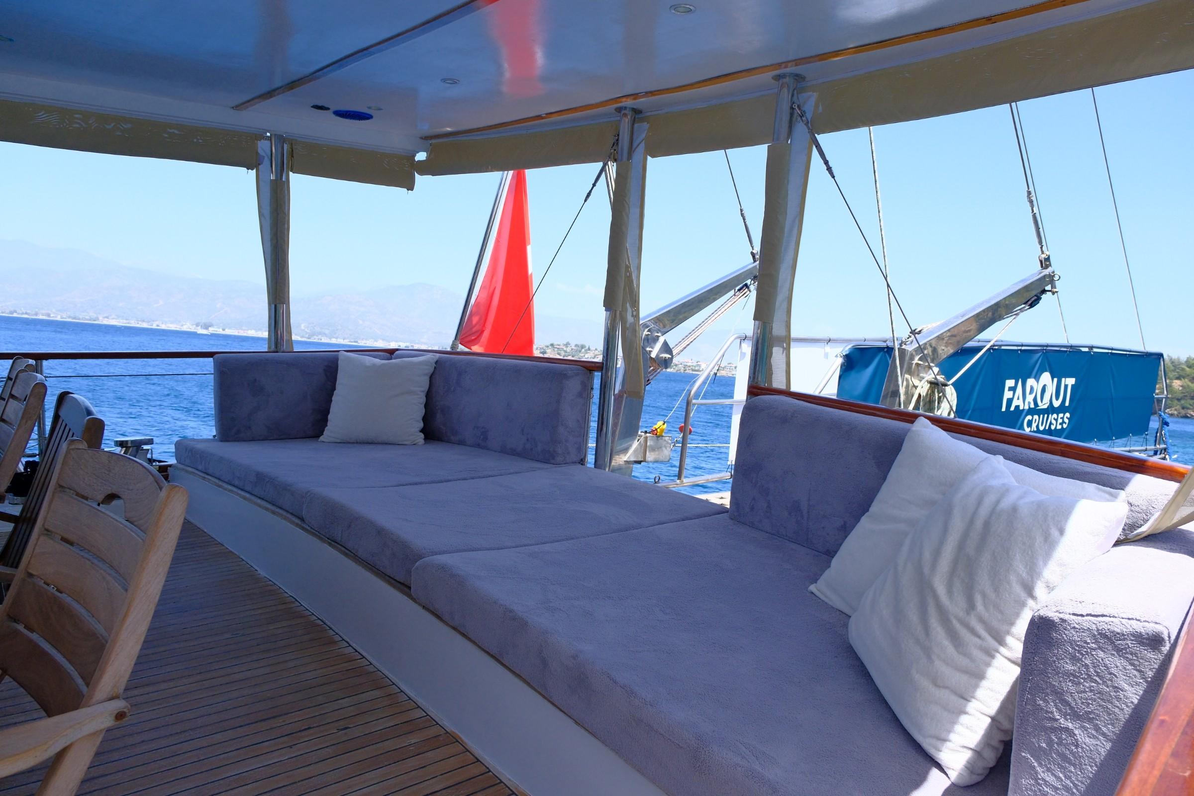 Gulet aft deck lounge area with blue cushioned seating under white canopy