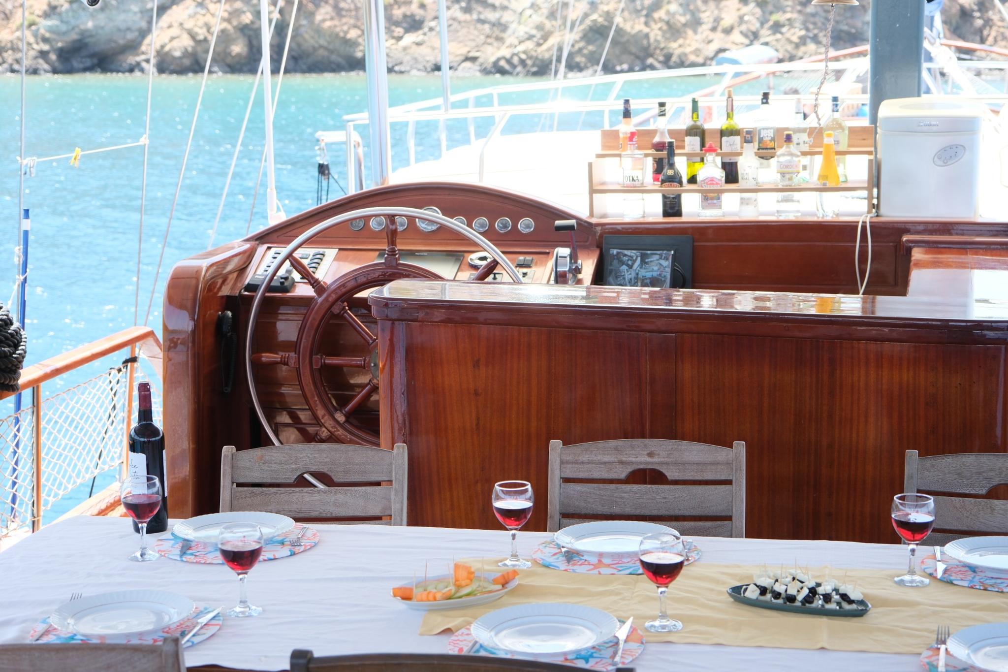 Gulet aft deck dining table set with red wine glasses and appetizer platters