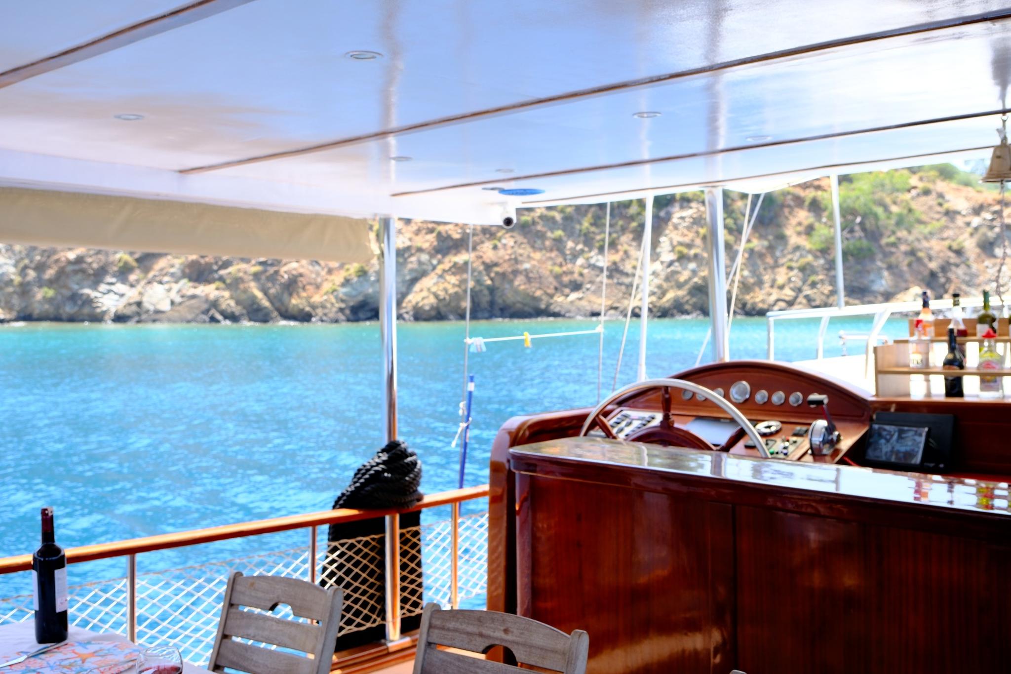 yacht helm station featuring wooden steering wheel and navigation instruments with turquoise waters