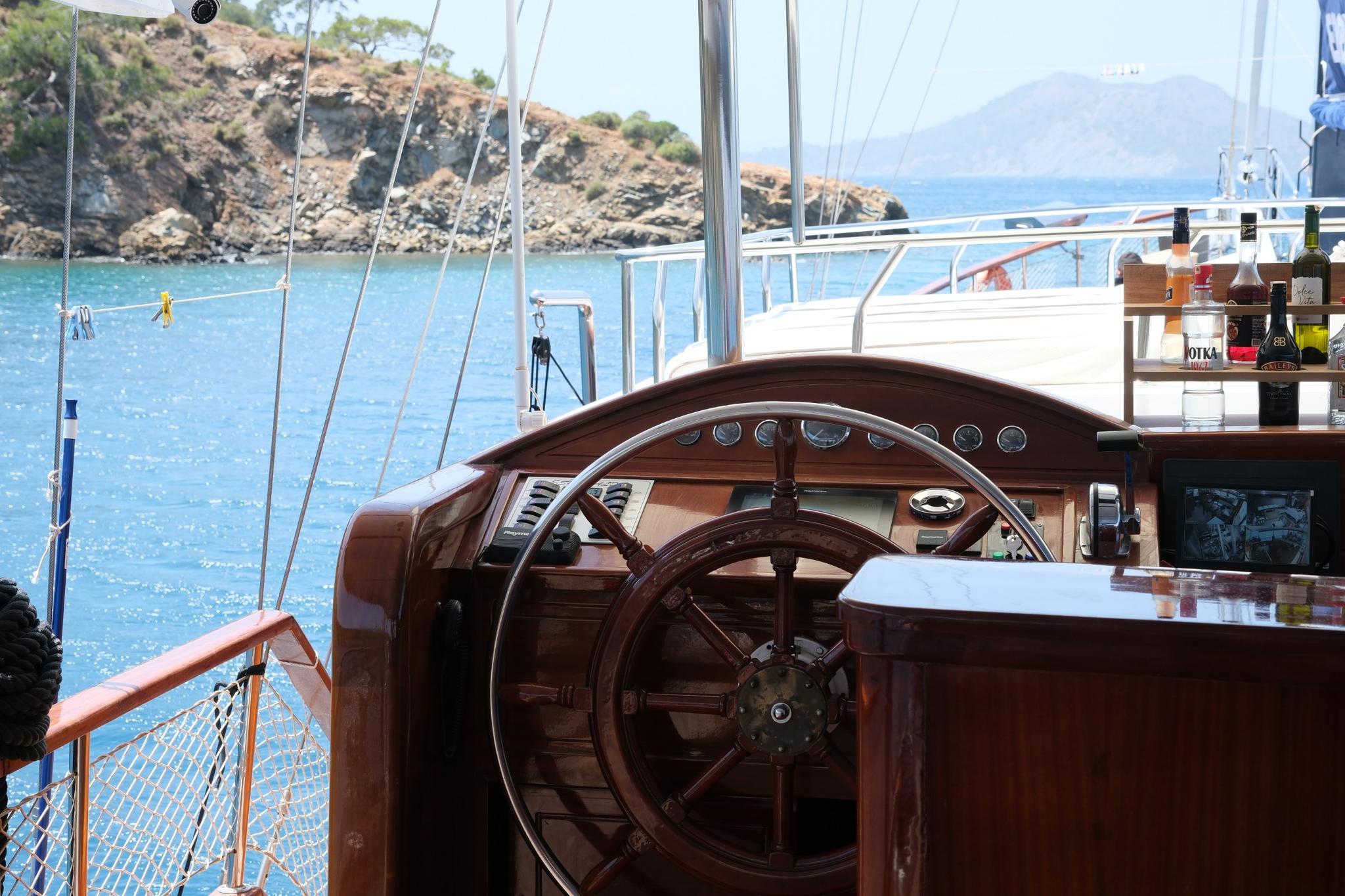 wooden ship's wheel at helm station with navigation instruments on traditional sailing yacht