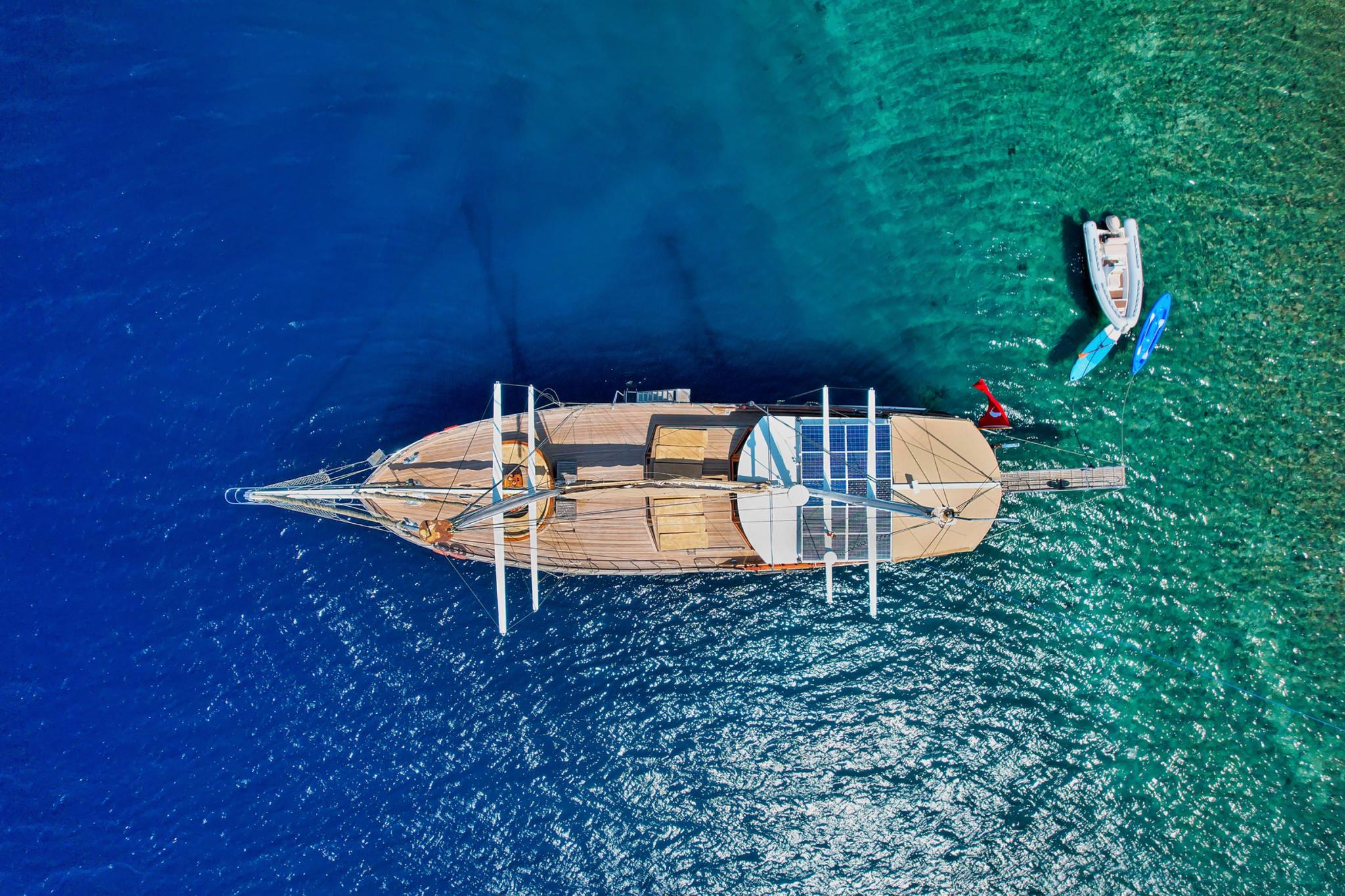 aerial drone shot of traditional gulet yacht anchored in crystal clear turquoise Mediterranean waters