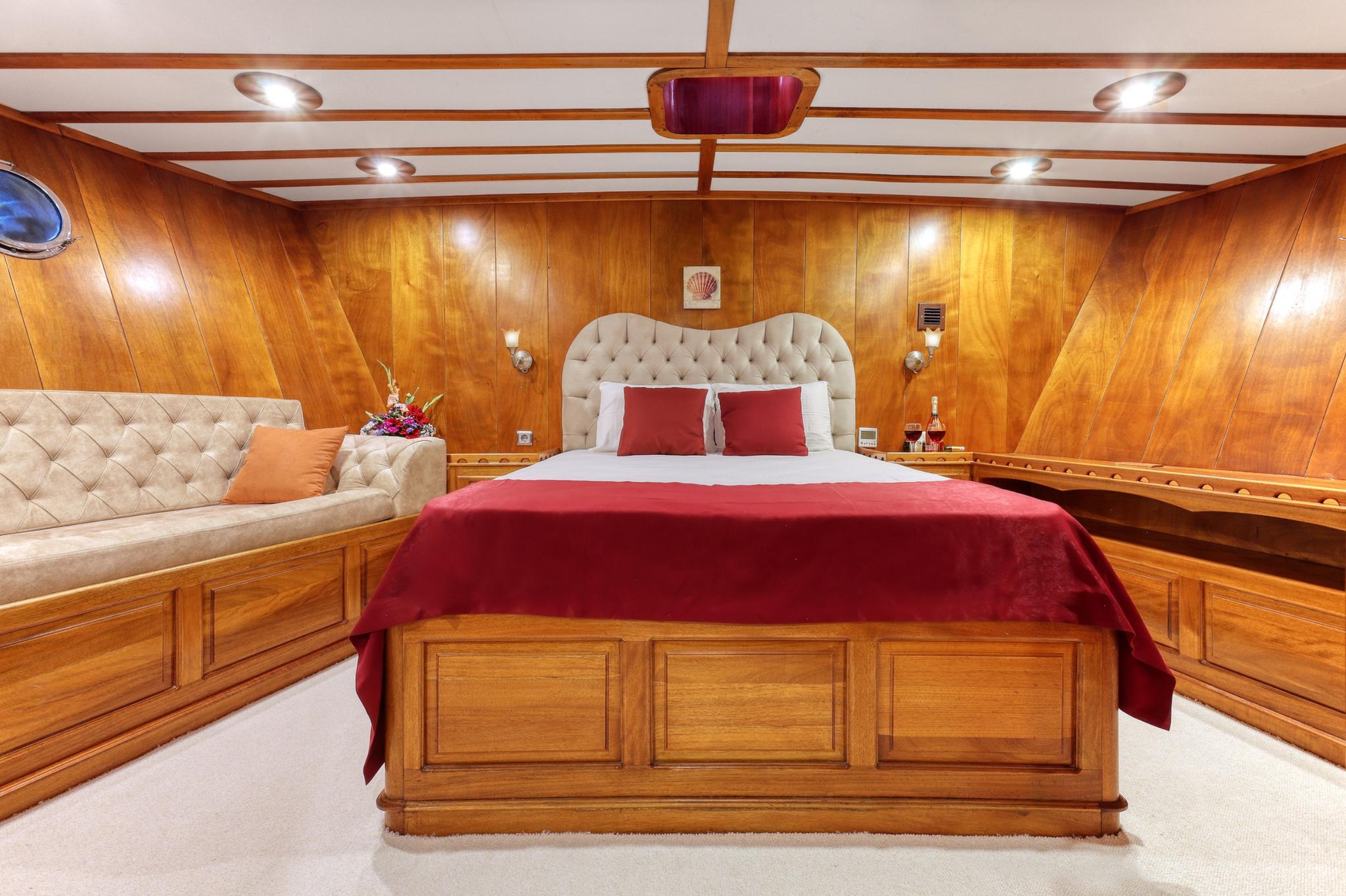 luxury yacht master cabin with king bed, red bedding, tufted headboard and wood paneling