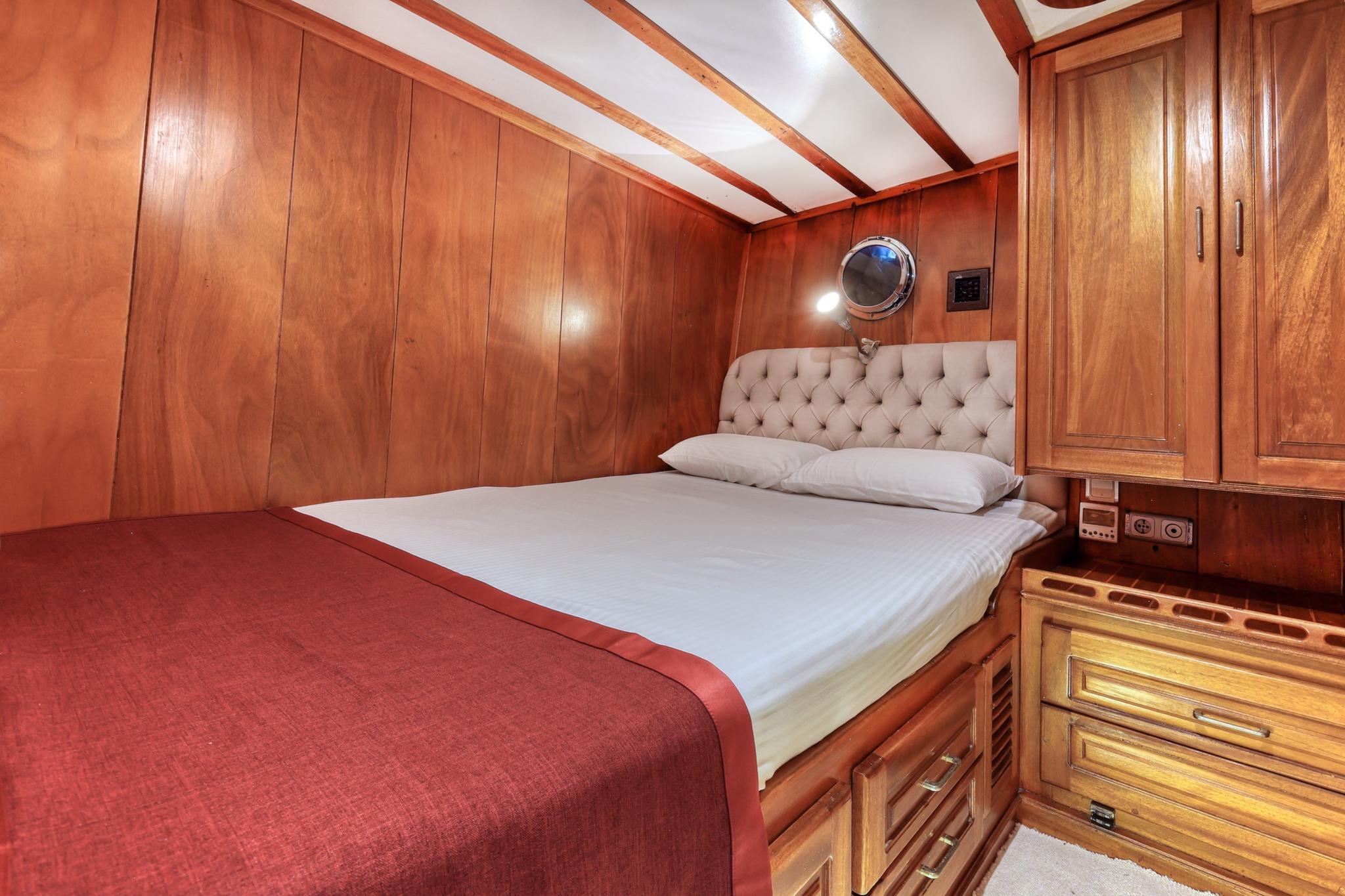 yacht guest cabin featuring double bed with tufted headboard and rich wood paneling