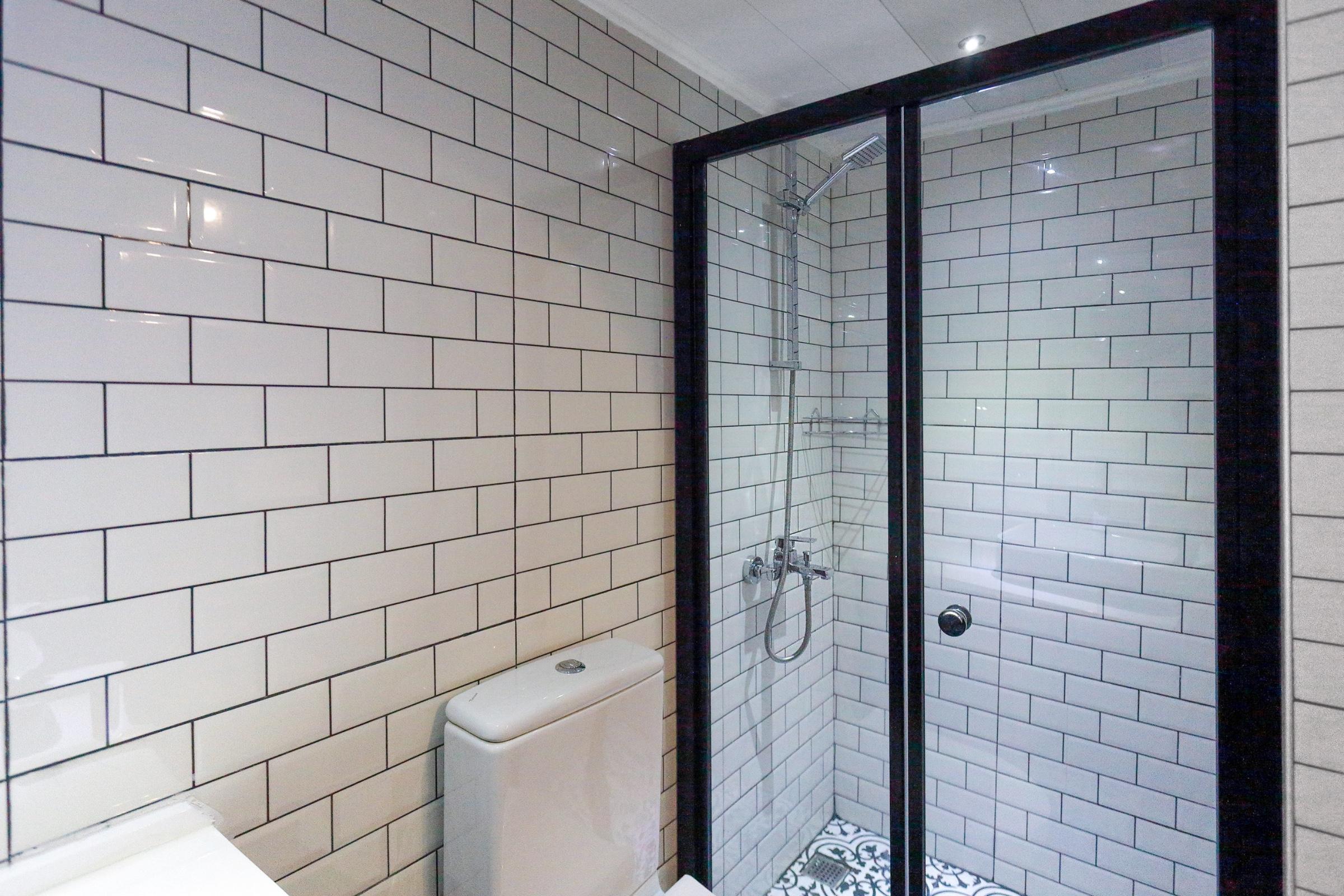 yacht bathroom featuring white subway tile walls, glass shower enclosure and toilet