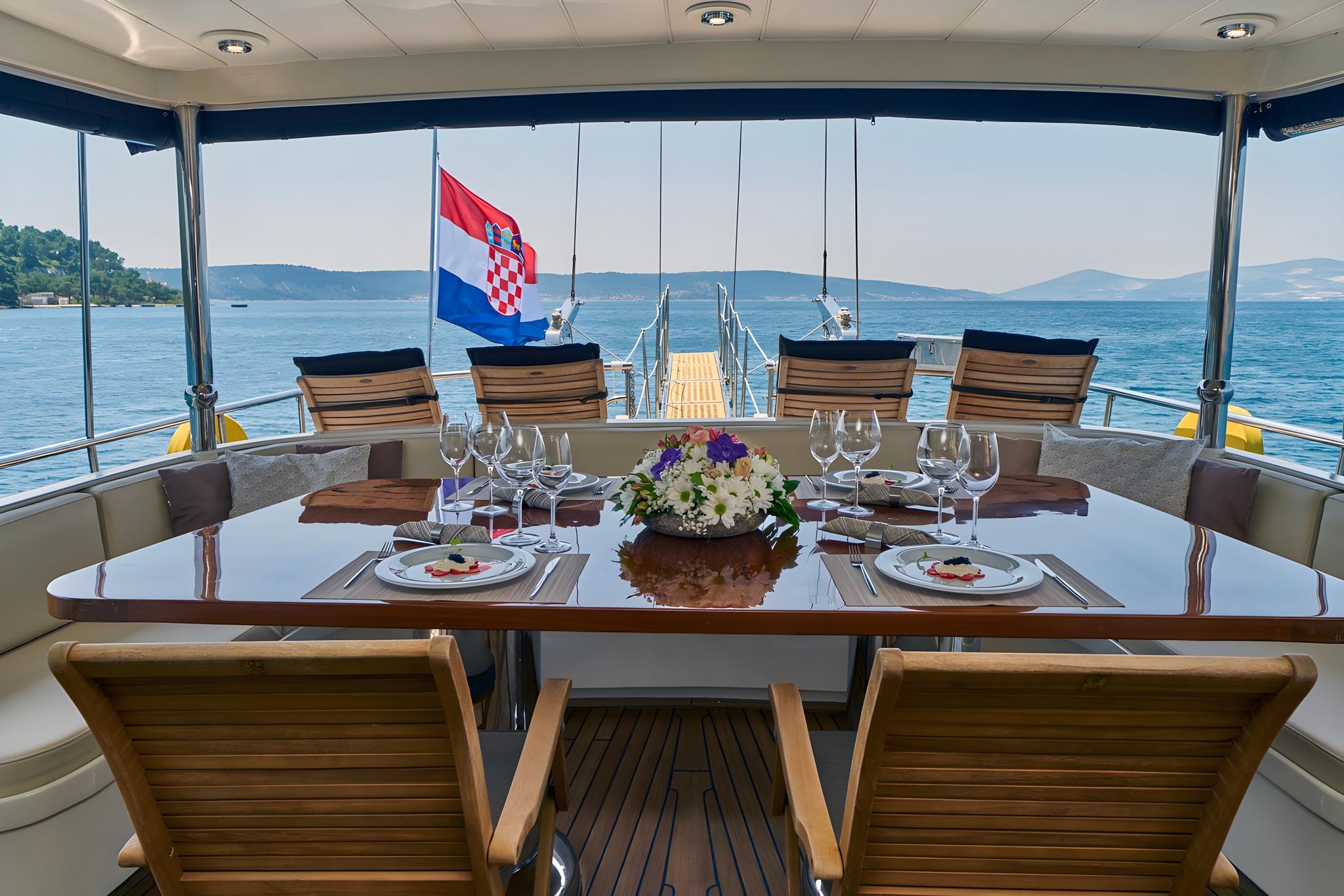 yacht aft deck dining area with formal table setting overlooking Croatian coastline