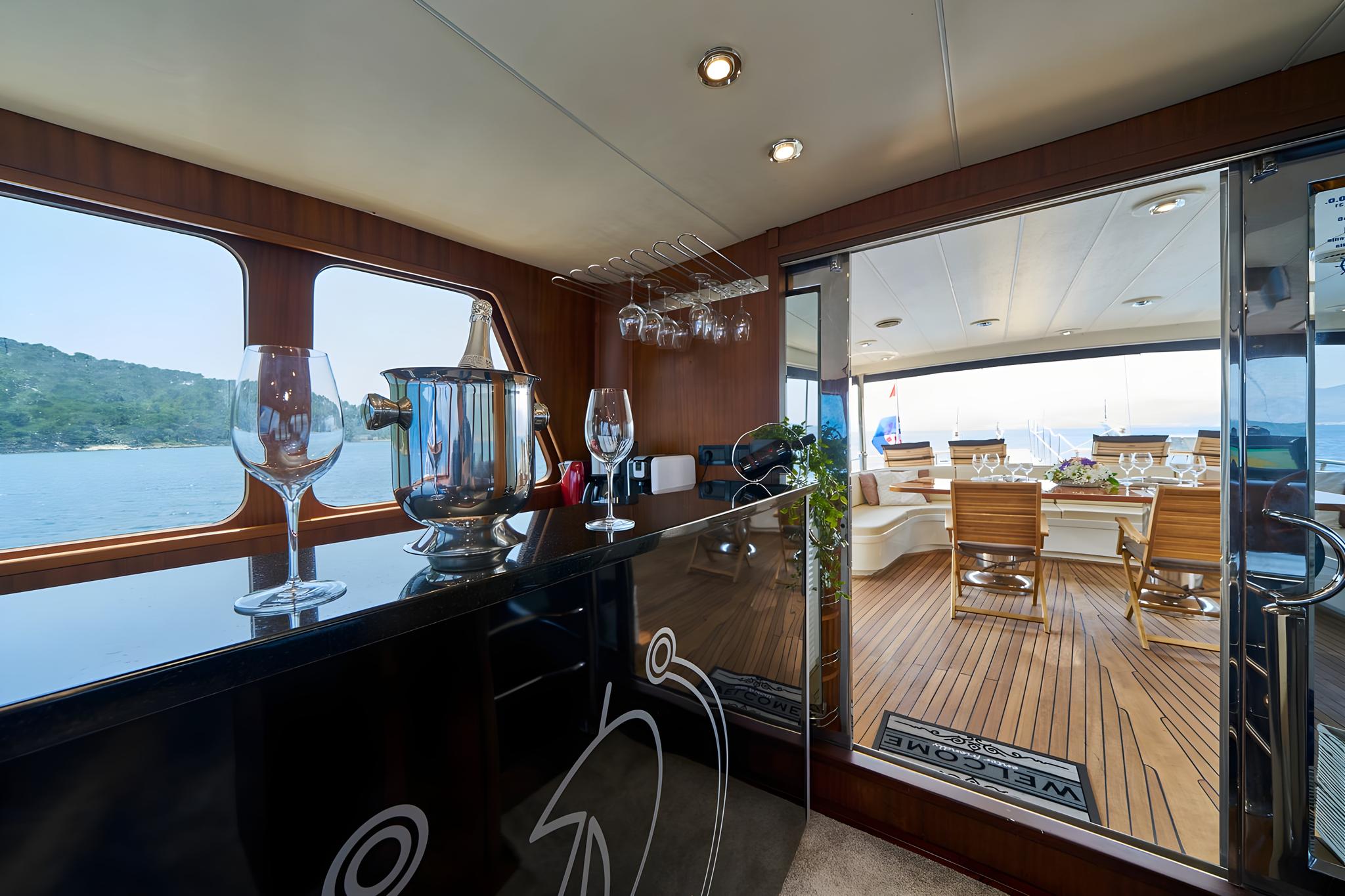 yacht interior bar with wine glasses, ice bucket, and view to outdoor dining deck