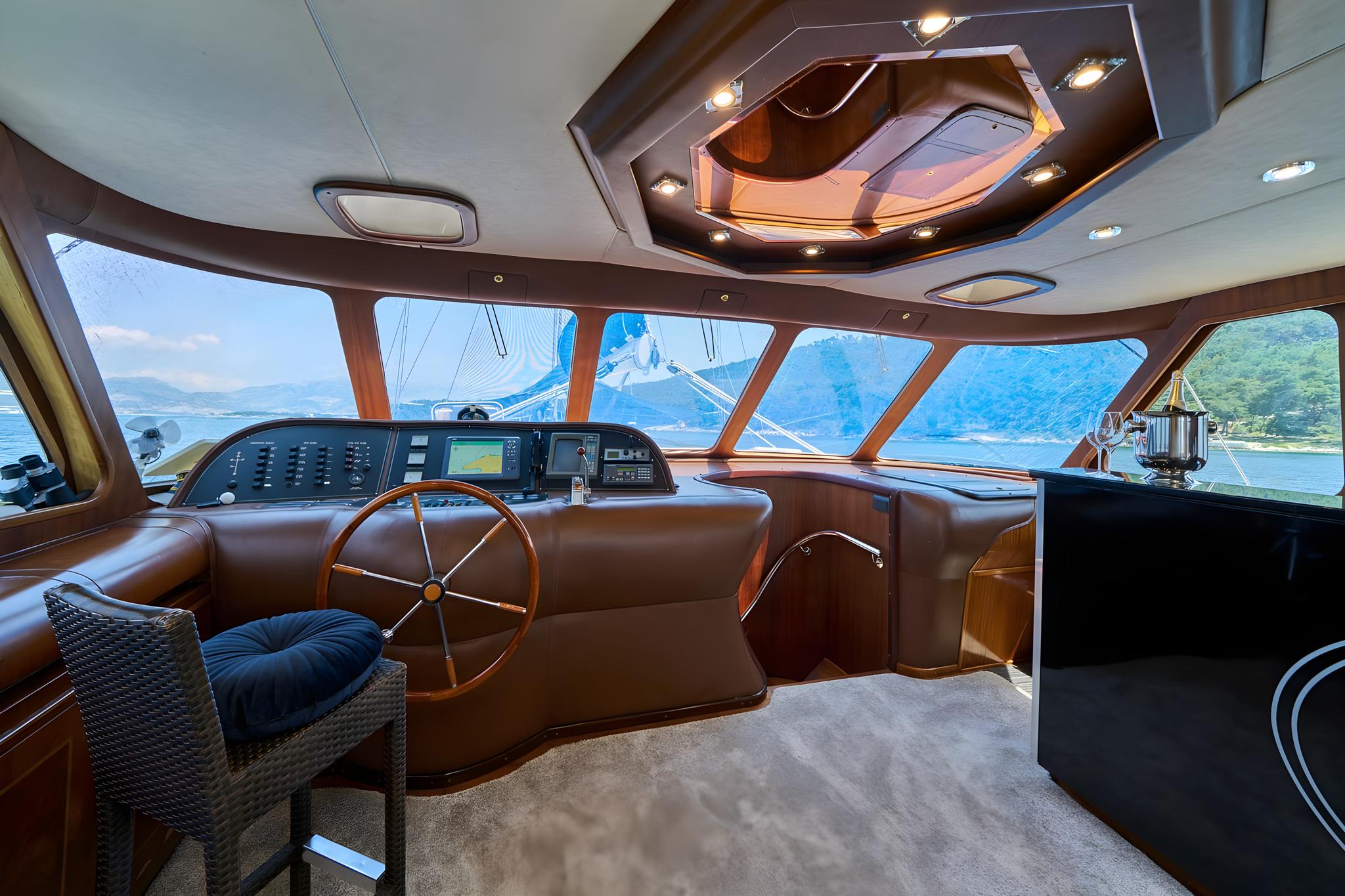 luxury yacht wheelhouse interior with steering wheel navigation console and panoramic windows