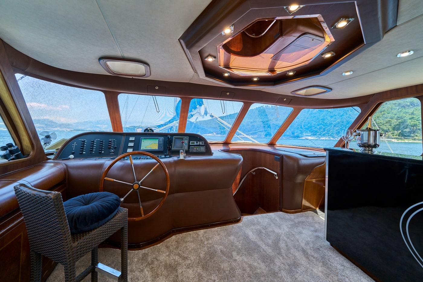 luxury yacht wheelhouse interior with steering wheel navigation console and panoramic windows