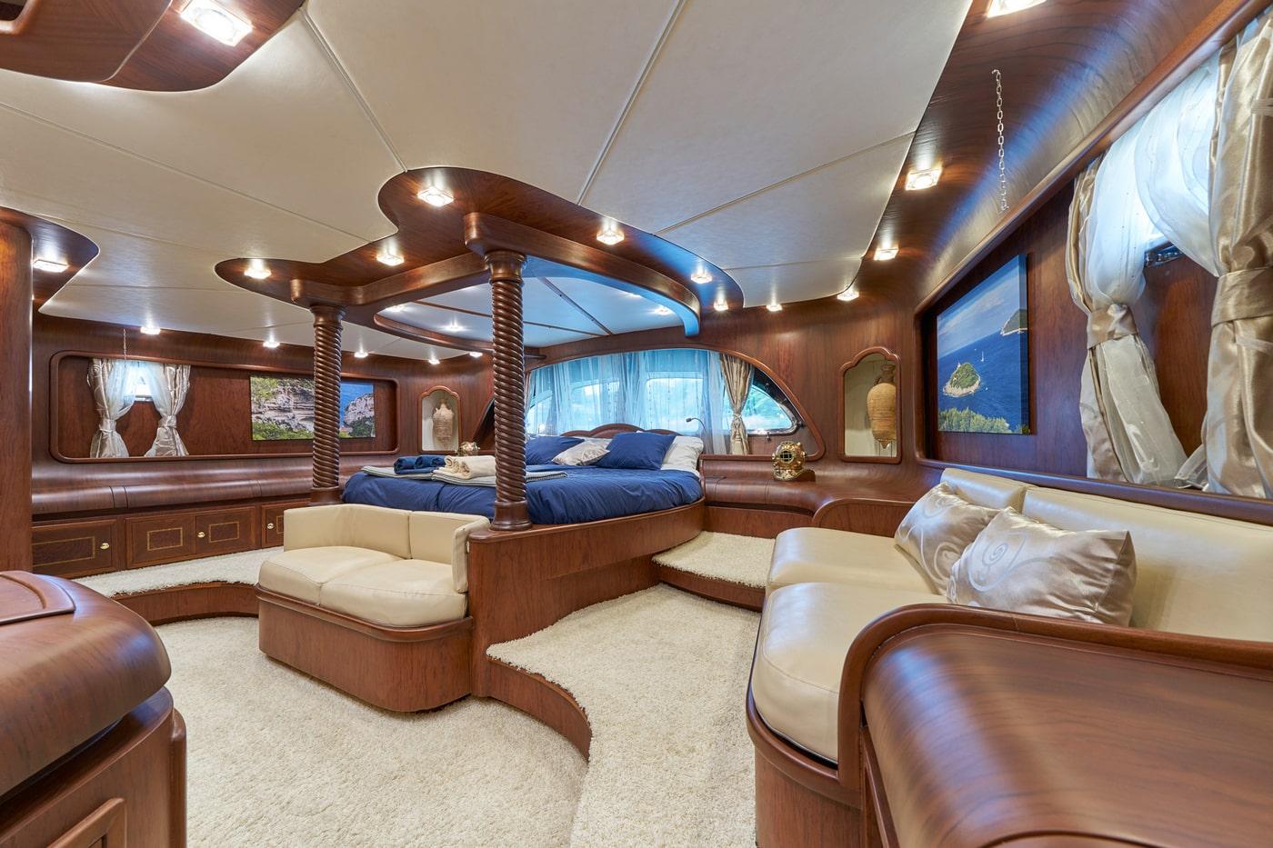 luxury yacht master cabin featuring circular bed with twisted rope posts and cream leather seating