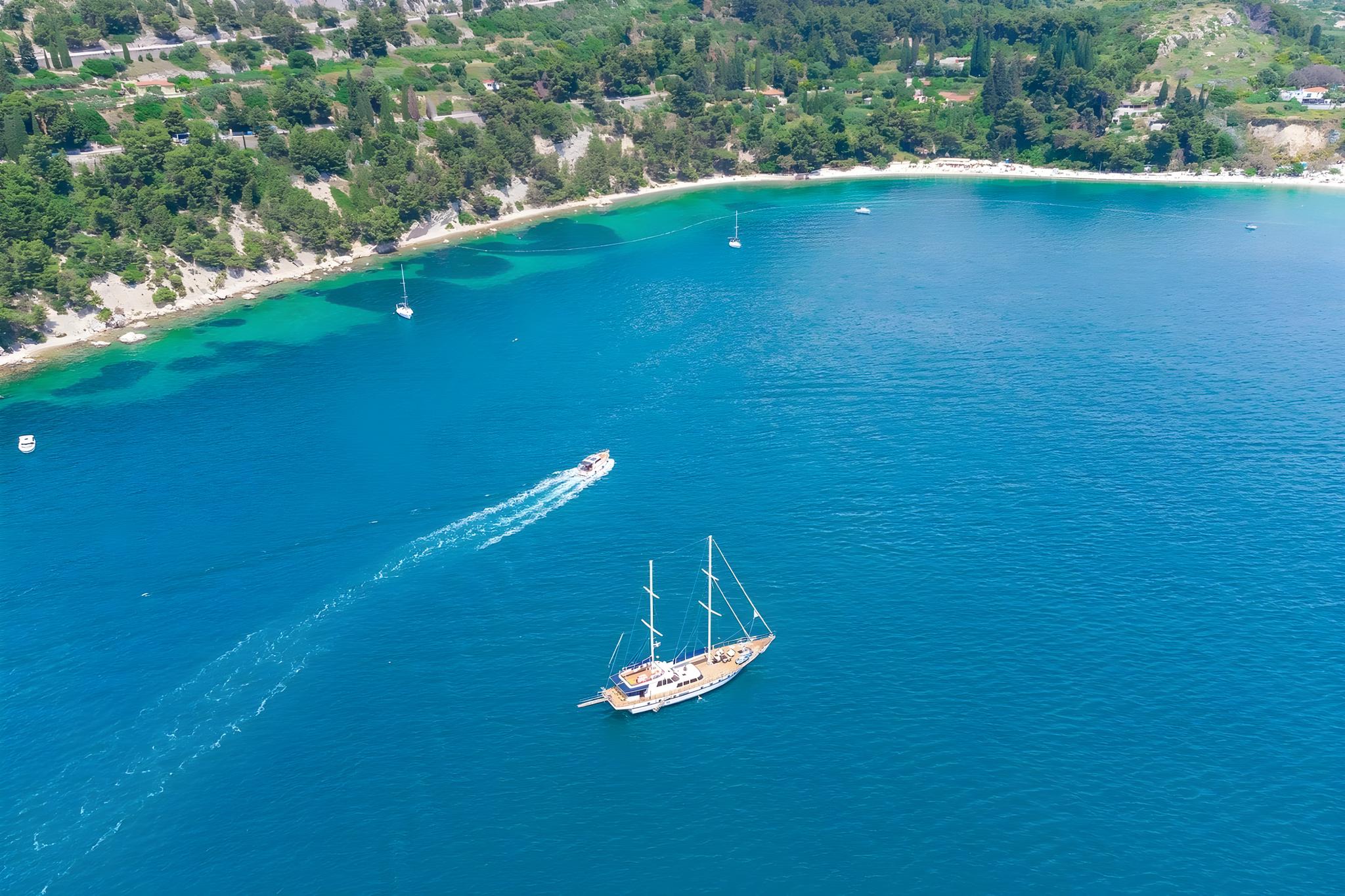 aerial view of traditional wooden gulet anchored in crystal clear turquoise Mediterranean bay