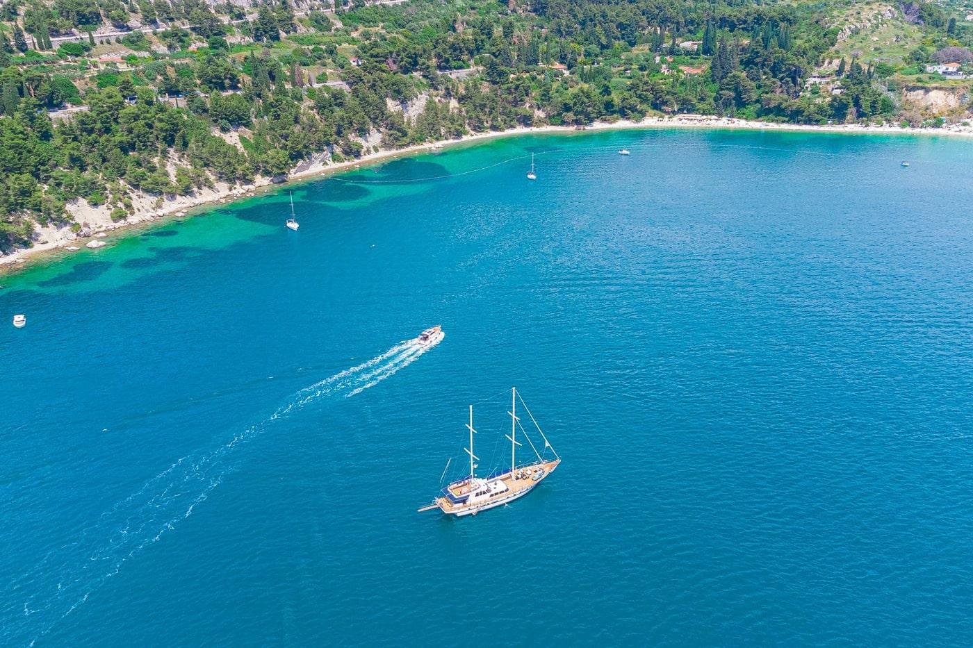 aerial view of traditional wooden gulet anchored in crystal clear turquoise Mediterranean bay