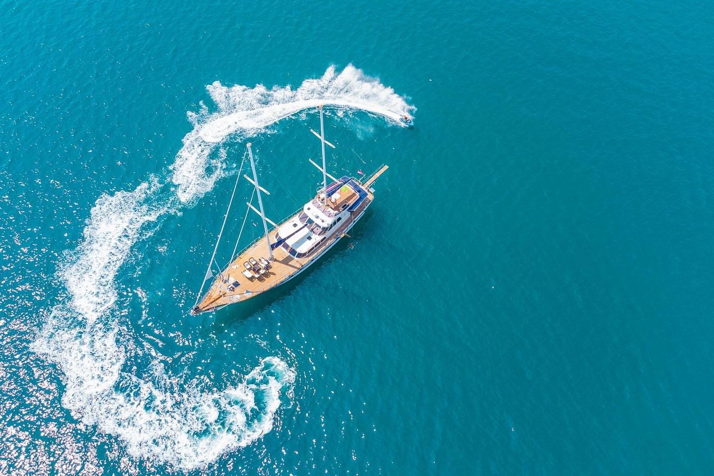 aerial view of traditional gulet yacht anchored in turquoise waters with distinctive white wake pattern