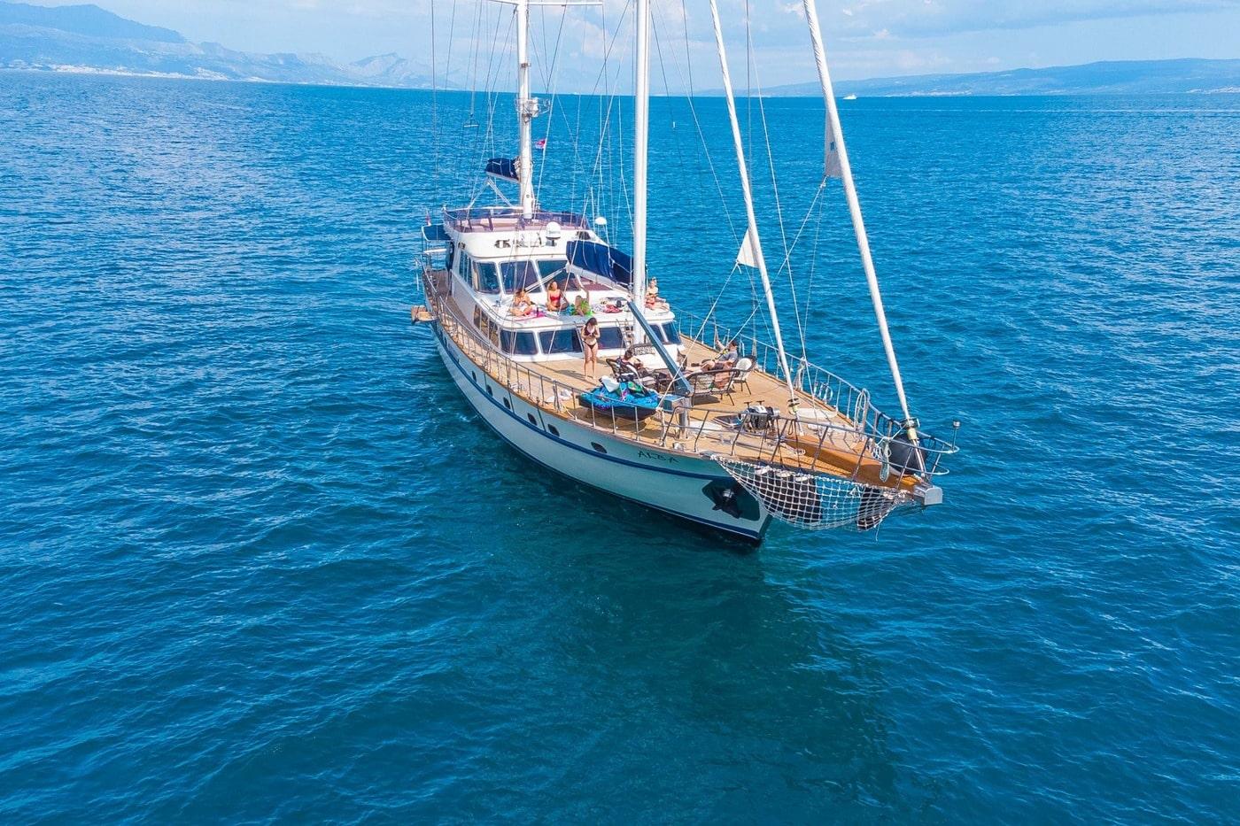 aerial view of traditional gulet yacht with two masts anchored in crystal blue waters