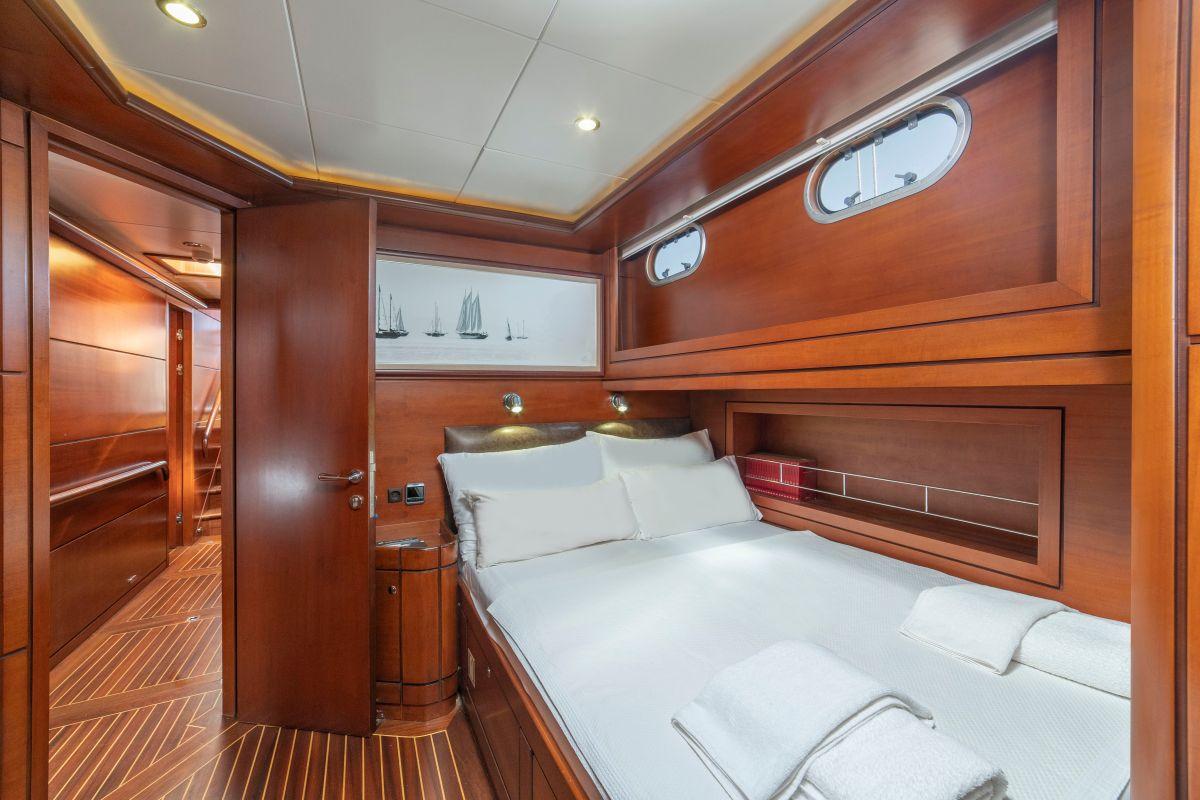 yacht guest cabin featuring double bed with white linens and rich wood paneling