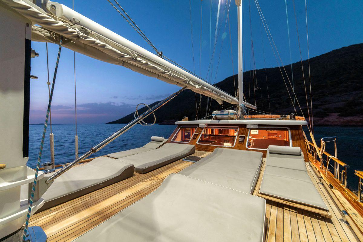 gulet bow deck with white sun cushions and sailing rigging at twilight