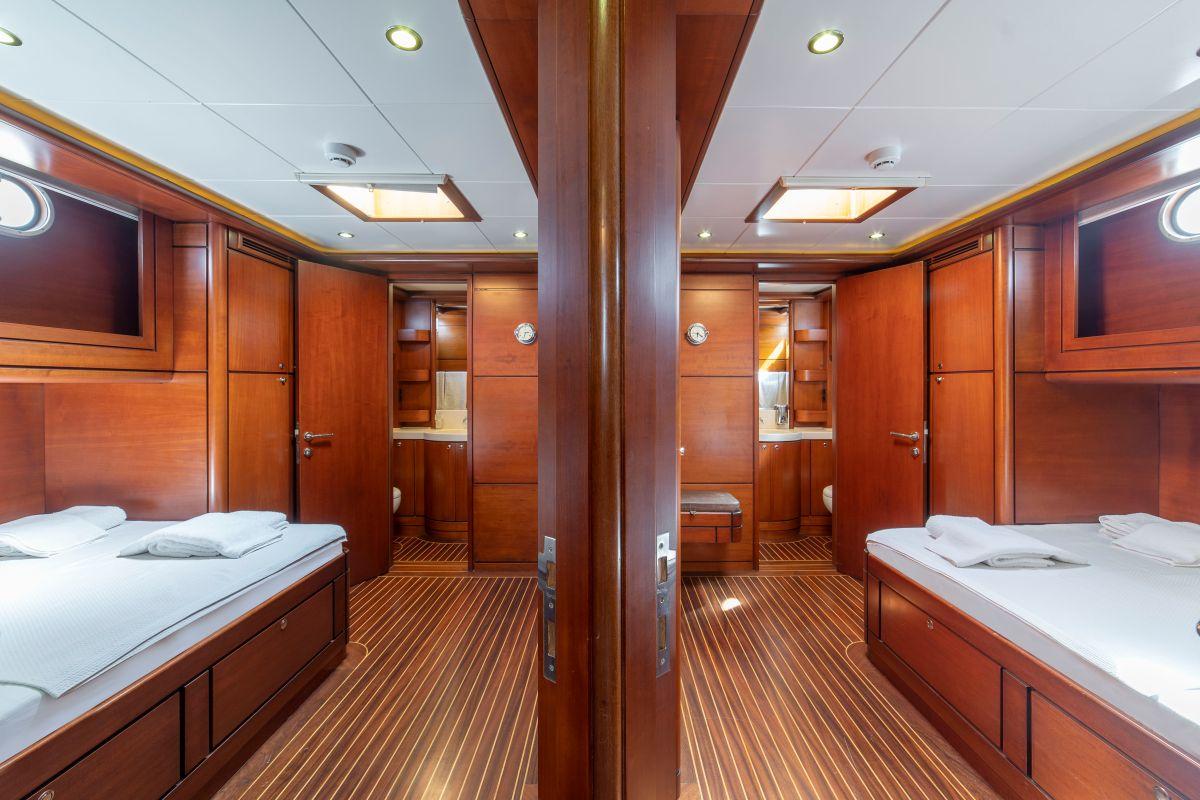 Guest cabin with twin beds, rich wood paneling, teak floors and two en-suite bathrooms
