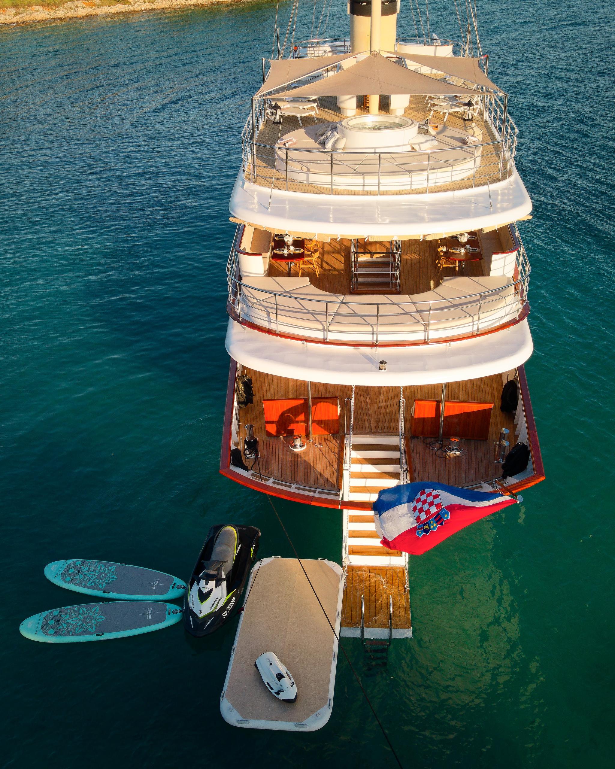 aerial view of luxury yacht stern showing swimming platform, paddleboards, jet ski and Croatian flag