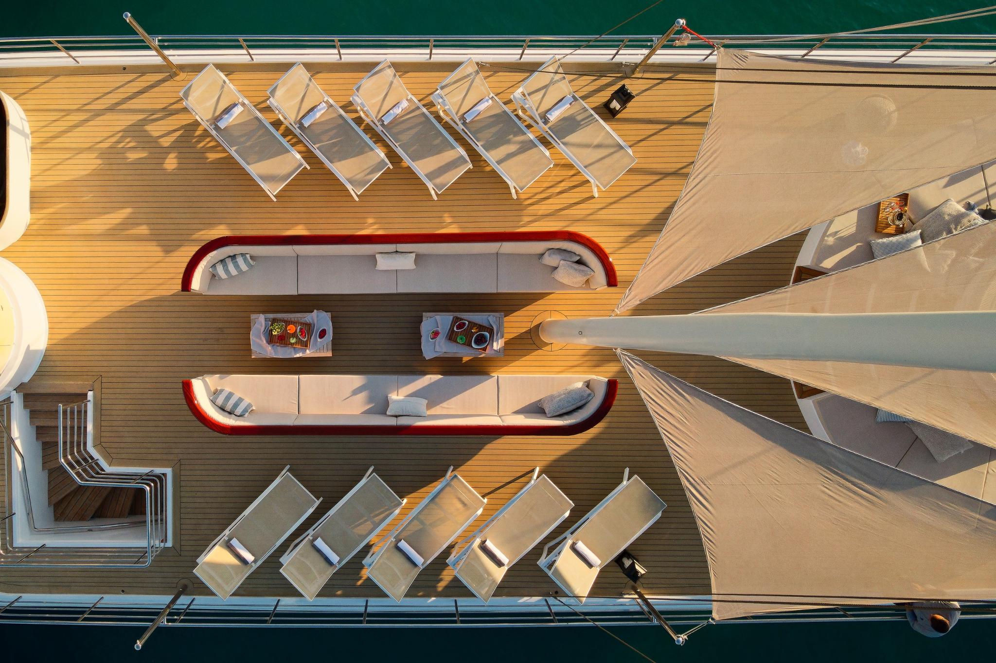 yacht main deck aerial view showing curved seating areas with red trim and sun loungers