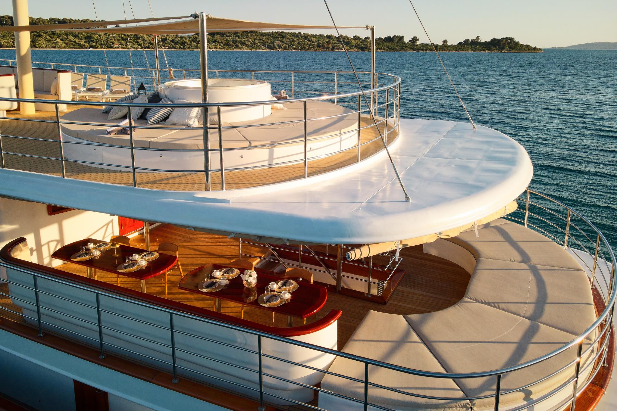 luxury yacht upper and lower deck areas with outdoor dining table and stainless steel railings