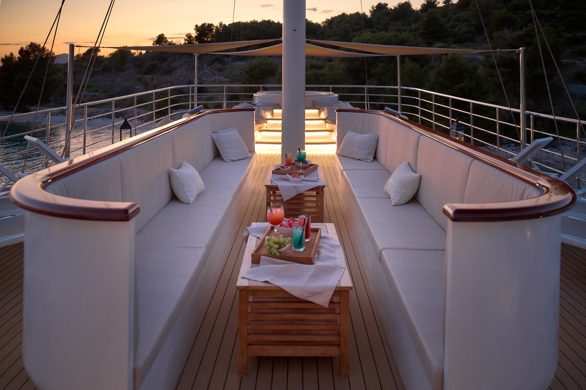yacht bow seating area with served drinks and fruit platter at sunset