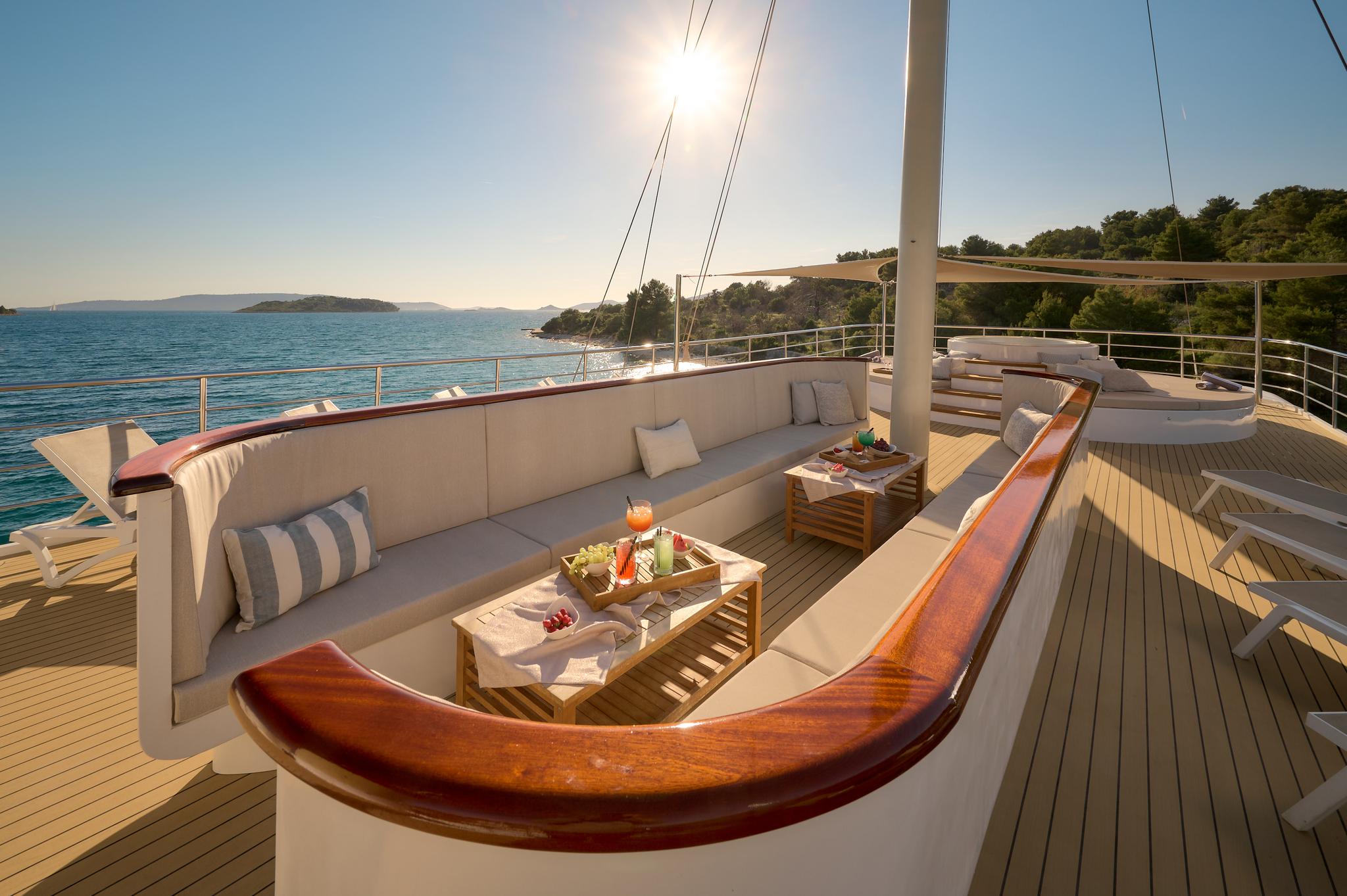 yacht aft deck with L-shaped seating, teak decking, cocktail service and coastal views