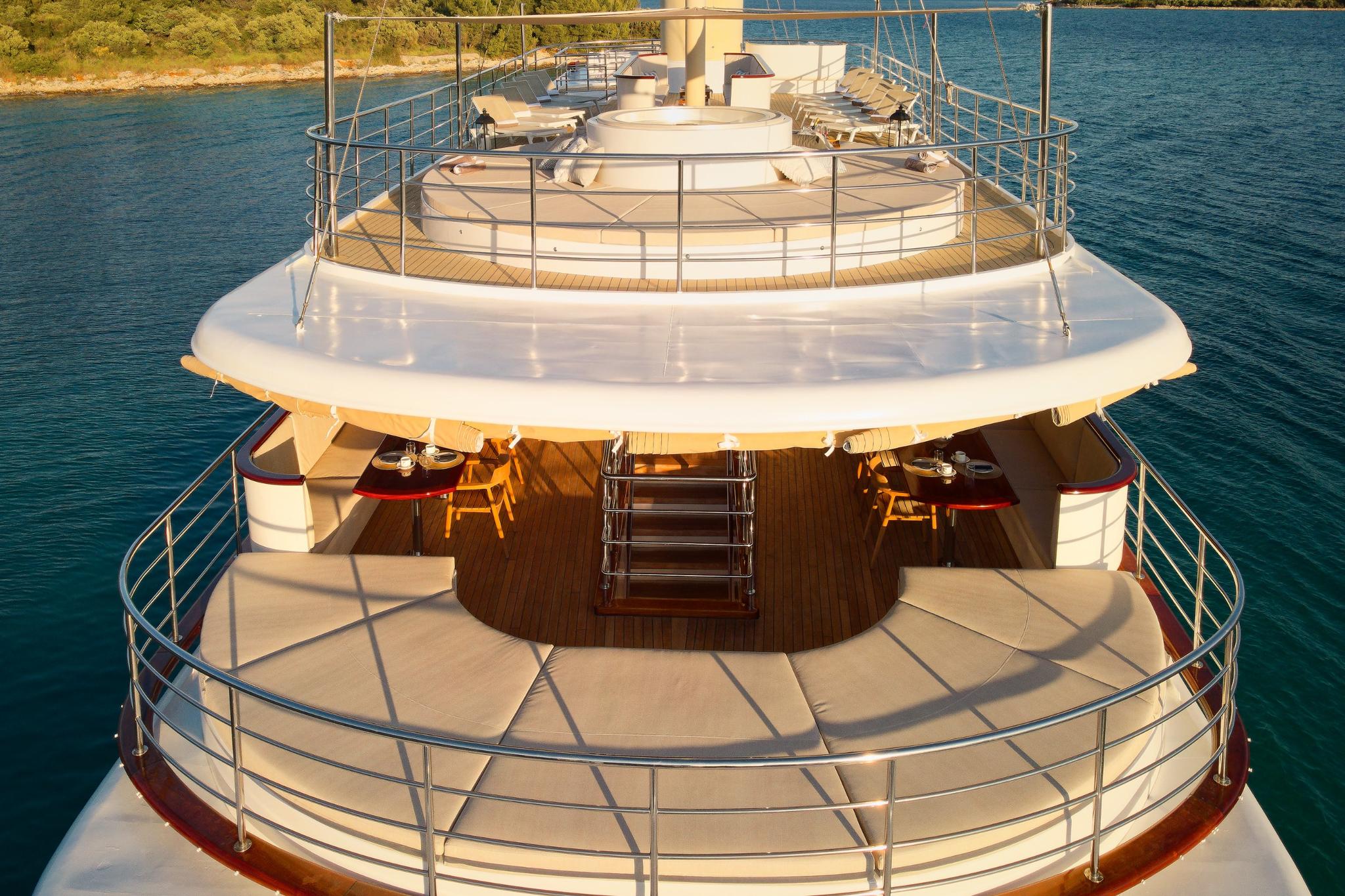 luxury yacht stern showing curved upper and lower decks with stainless steel railings