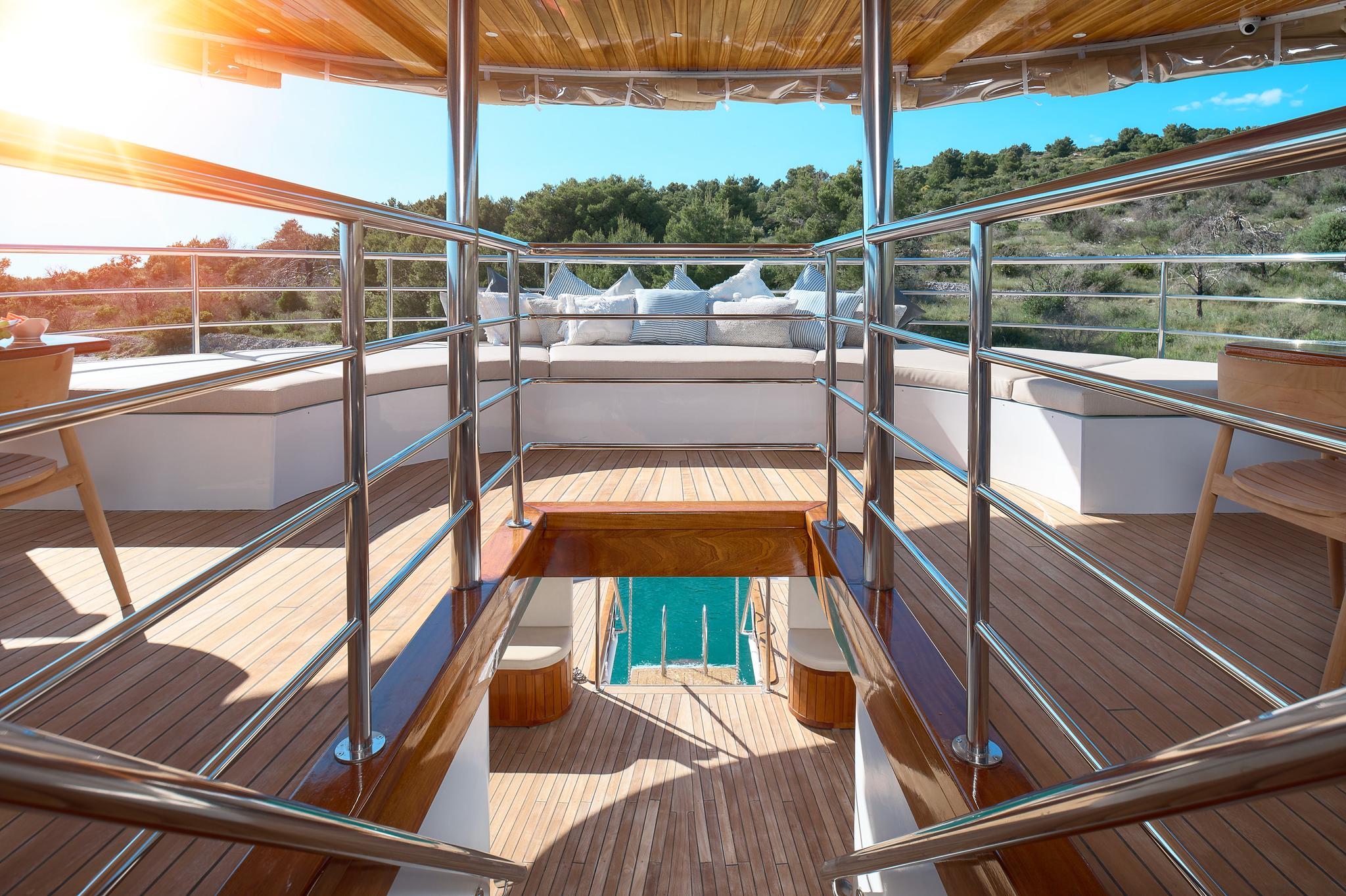 yacht upper deck with teak flooring, stainless steel railings and stairs to lower level