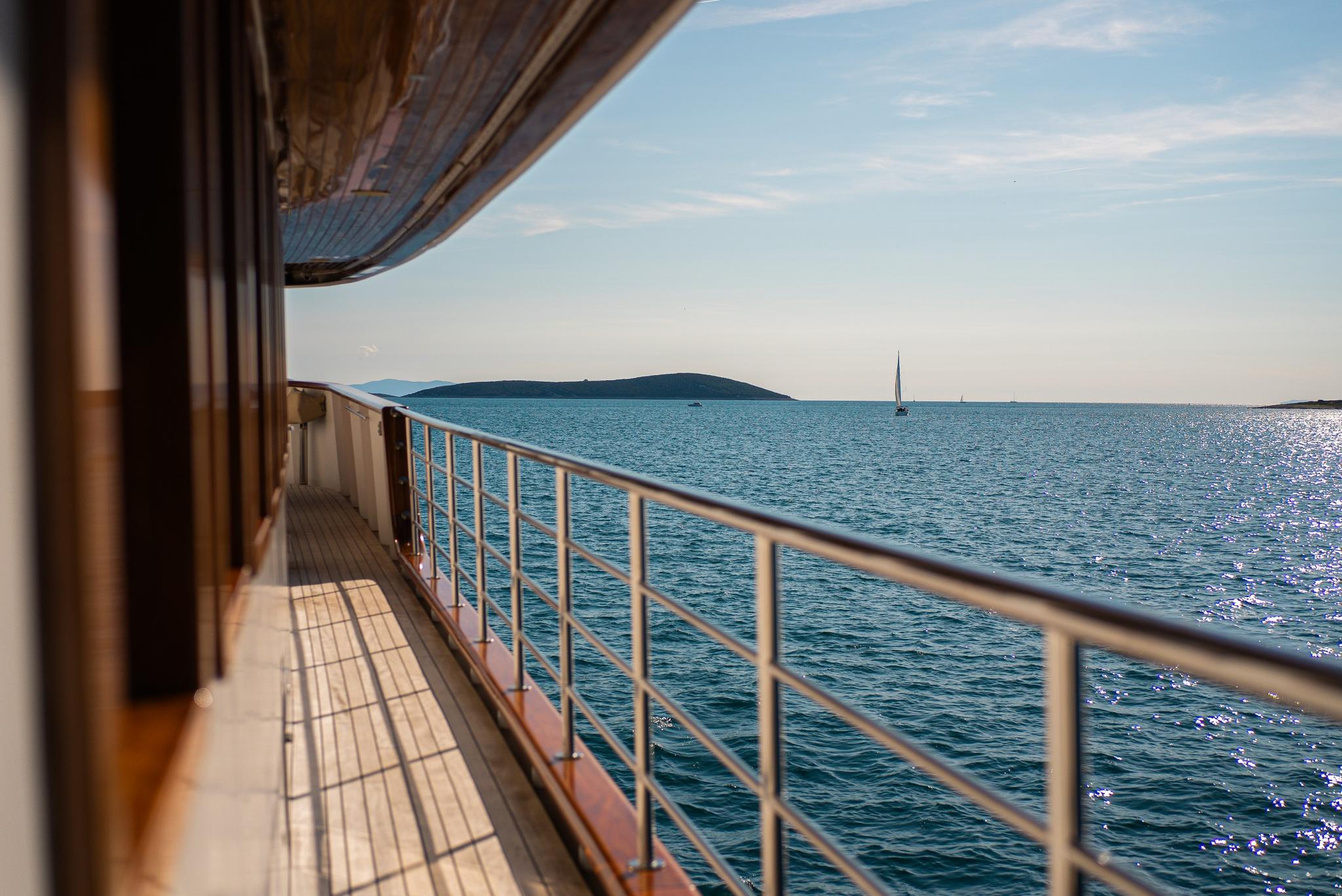 yacht side deck walkway with stainless steel railings overlooking turquoise waters and distant islands